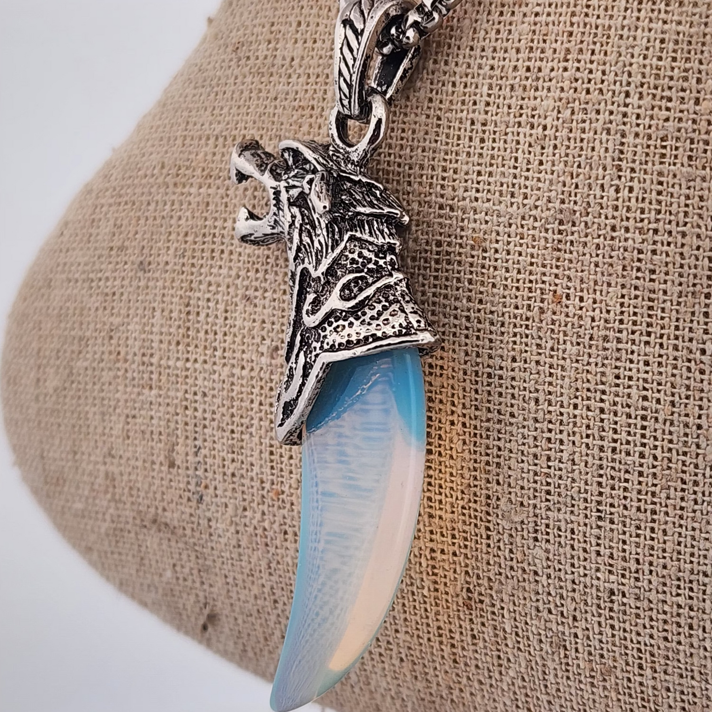 Necklace with a wolf pendant and blue stone on a beige fabric background