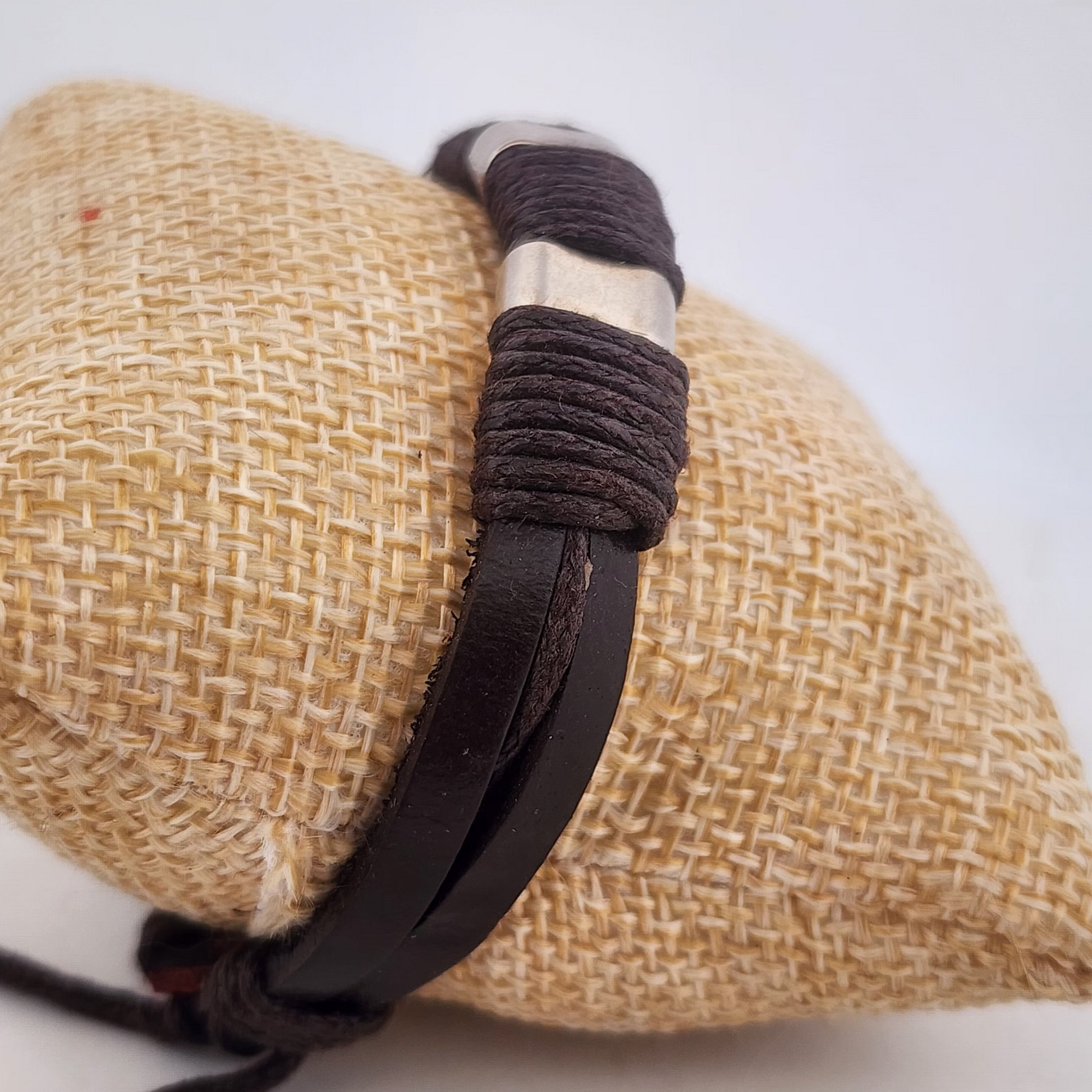 Bracelet with brown leather strap and silver clasp on a textured beige surface