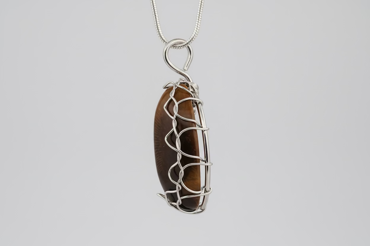 Tiger's eye pendant with silver wire wrapping on a beige fabric background