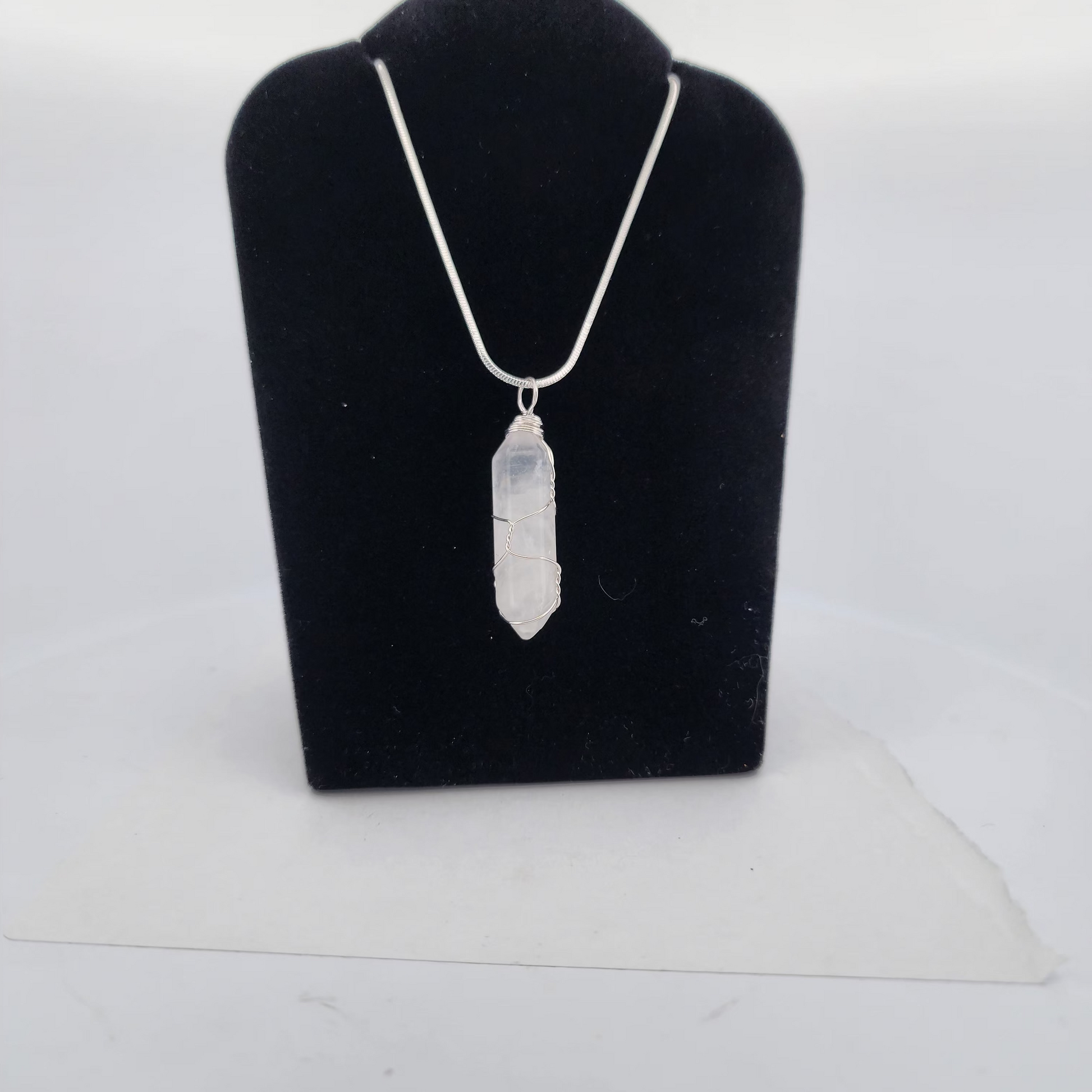 Silver necklace with a pendant on a black velvet stand against a white background