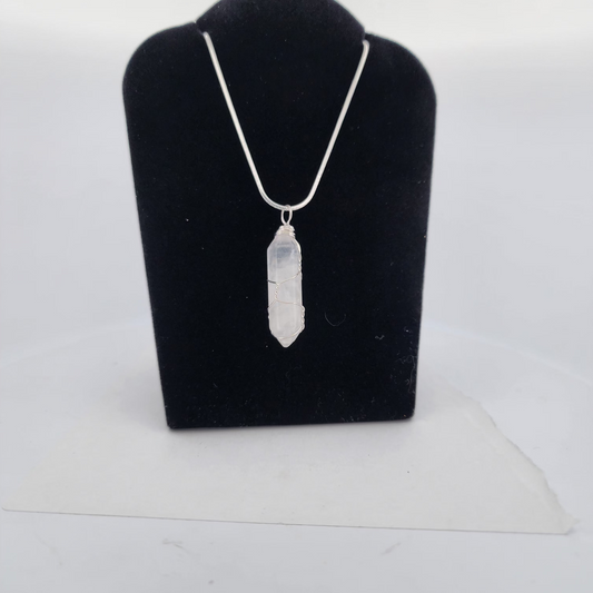 Silver necklace with a pendant on a black velvet stand against a white background