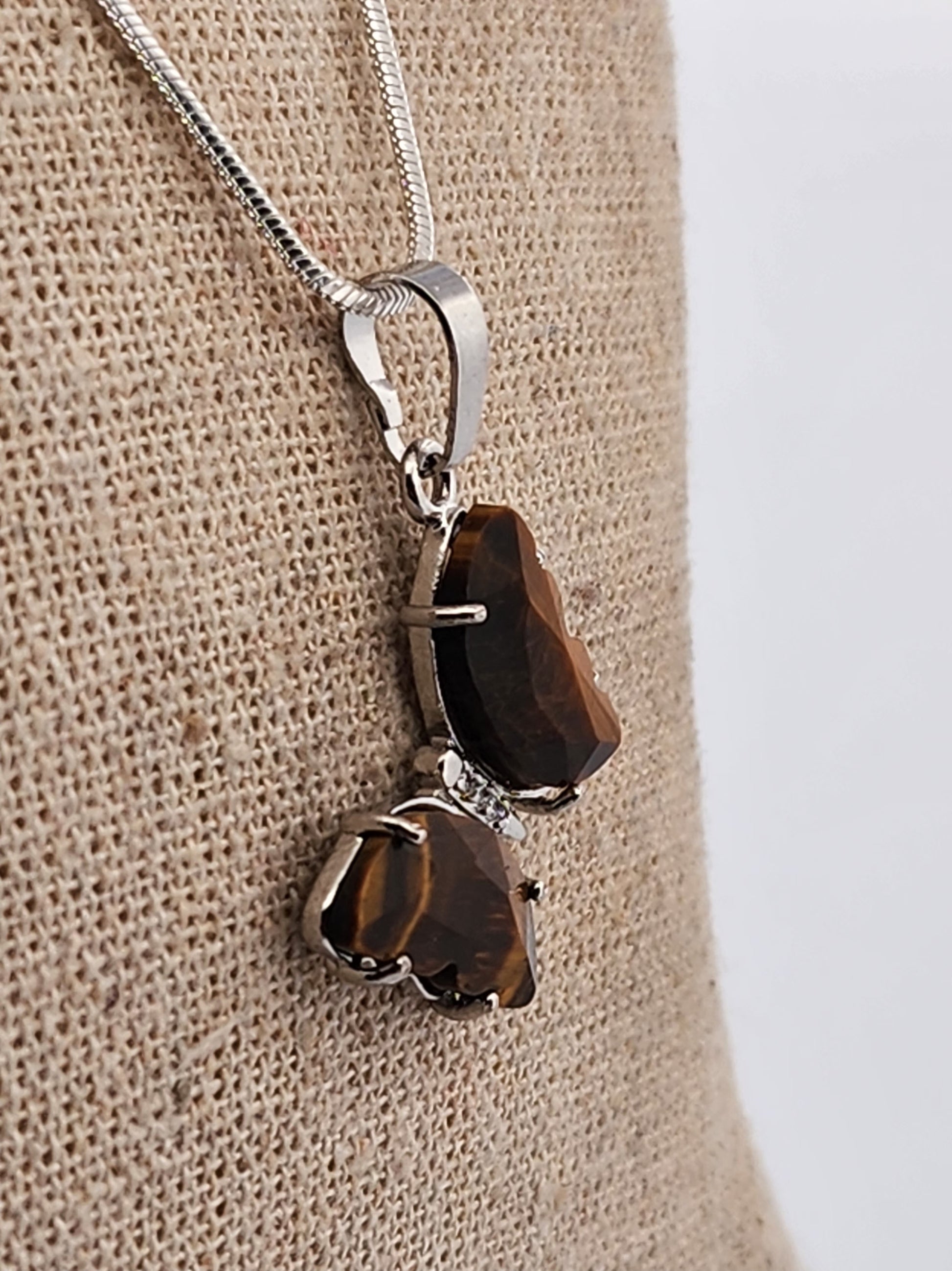 Silver necklace with a brown pendant on a beige fabric background