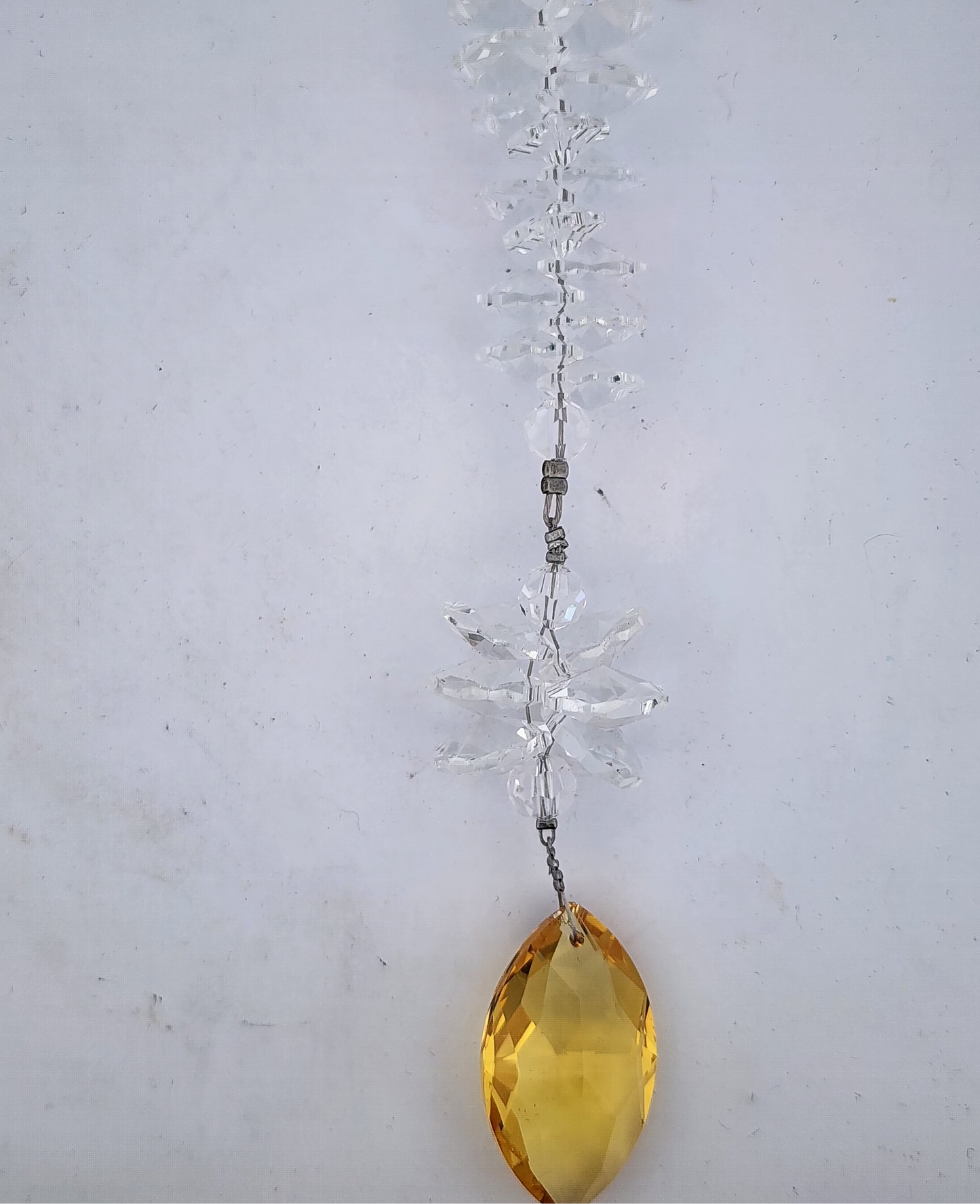 Crystal hanging decoration with a yellow teardrop shape on a white background