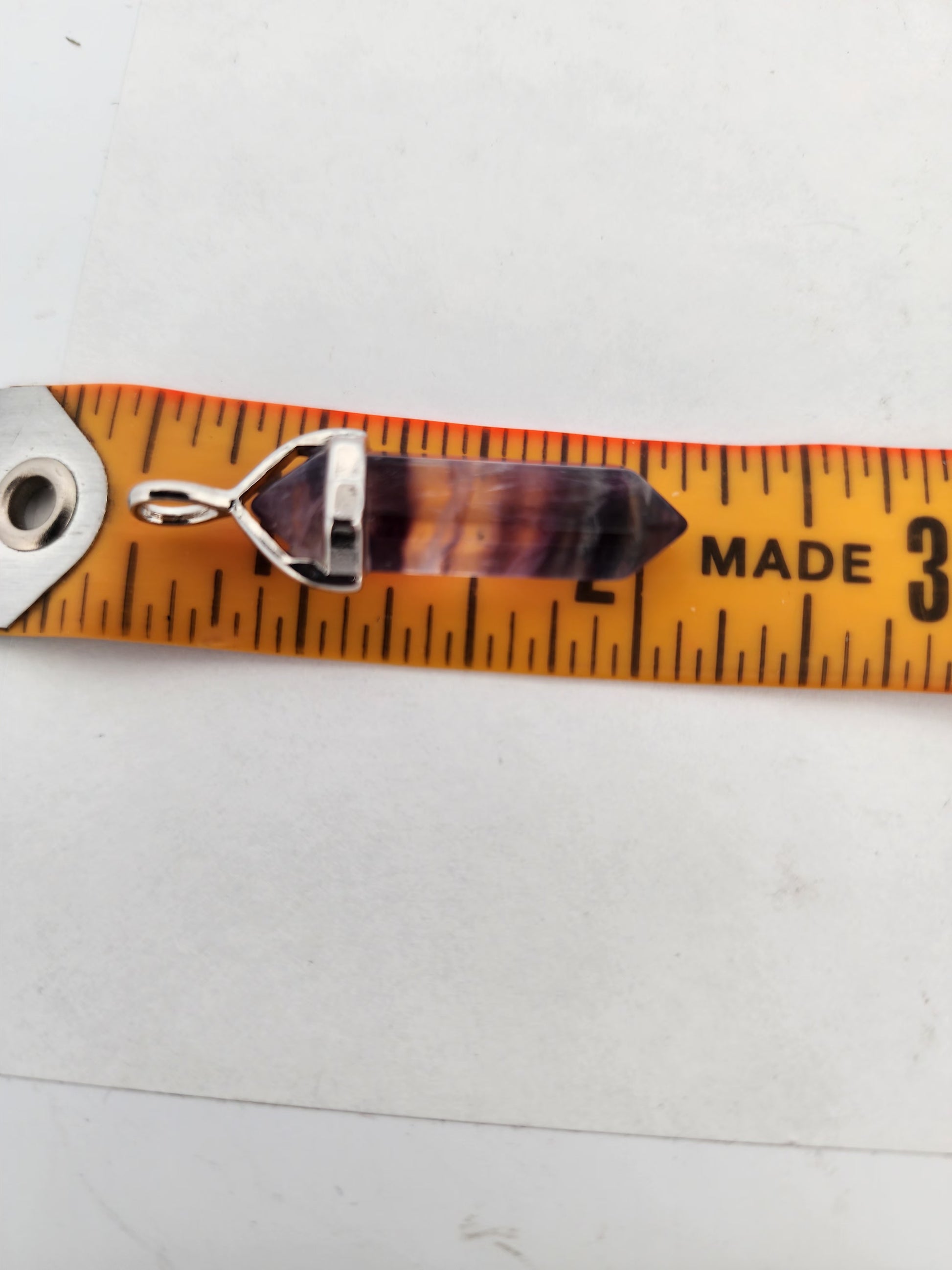 Orange ruler with a silver pendant on a white background