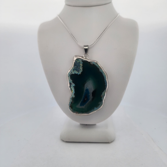 Necklace with a large green pendant on a mannequin bust against a white background
