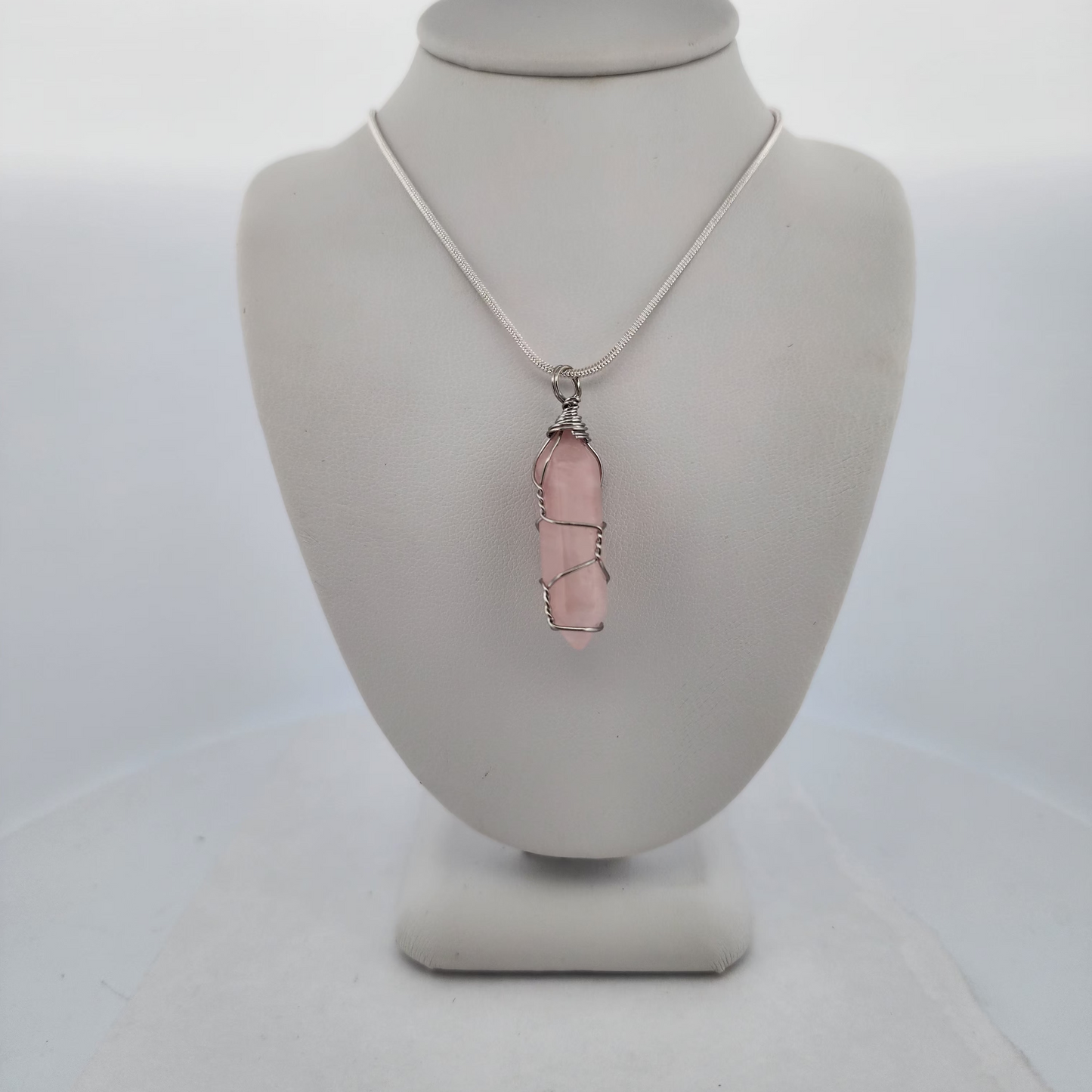 Necklace with a pink pendant on a mannequin bust against a white background