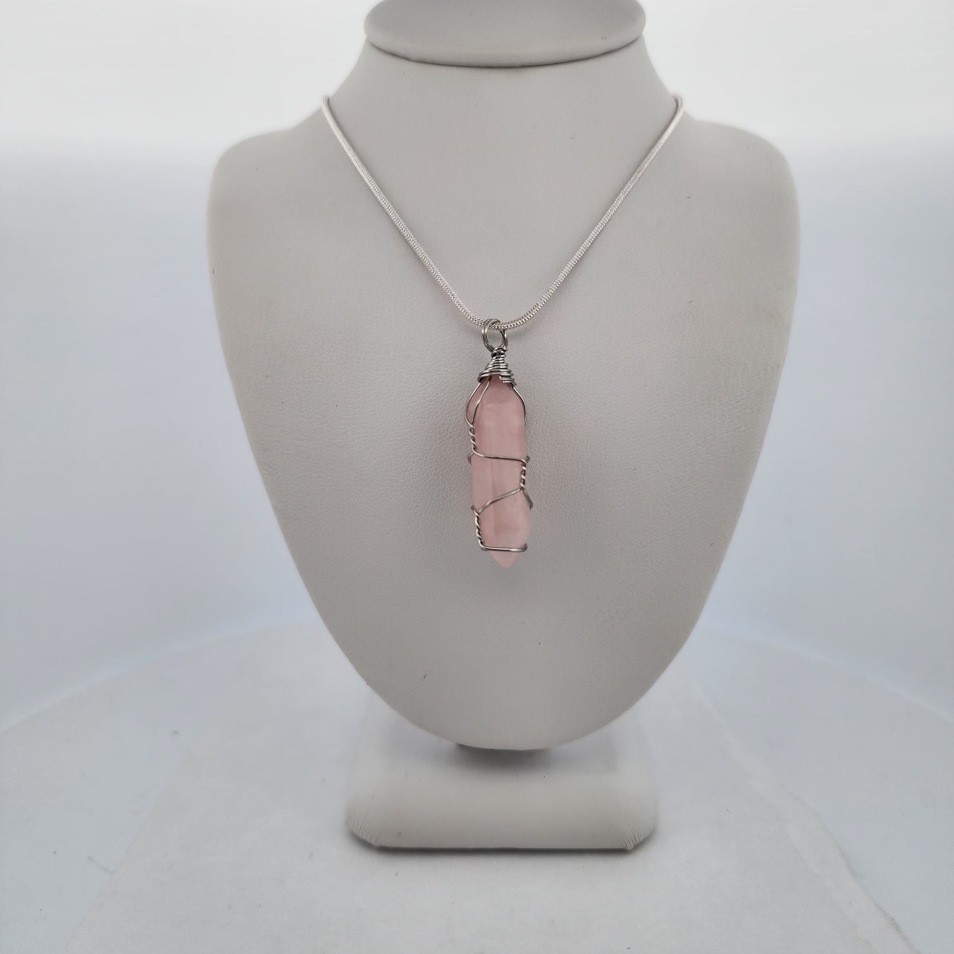 Necklace with a pink pendant on a mannequin bust against a white background