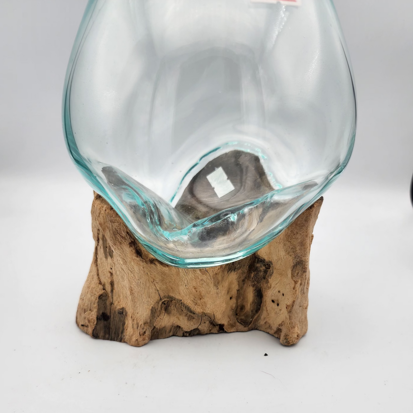 Clear glass vase on a wooden base against a white background