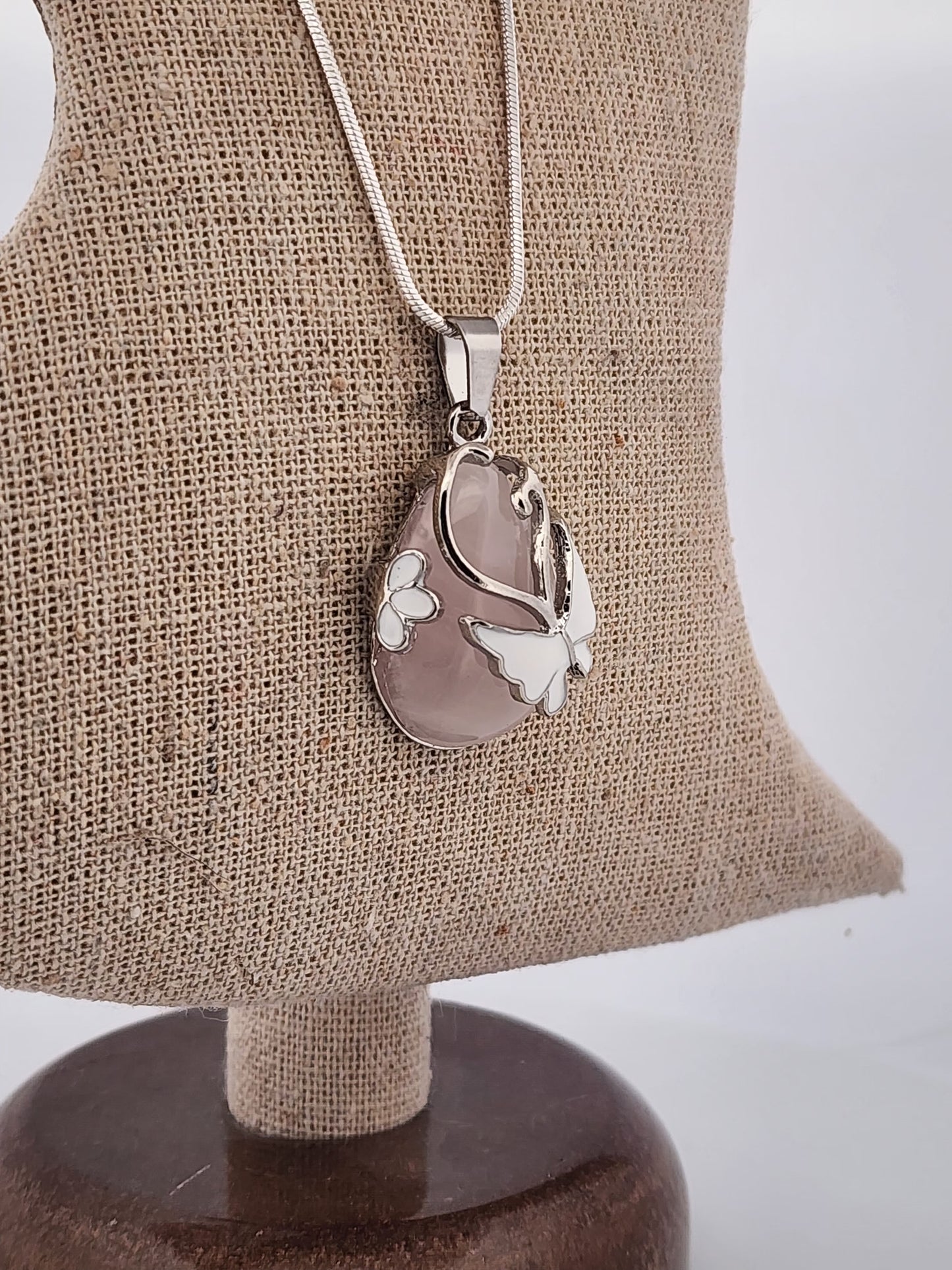 Silver pendant necklace on a mannequin bust with a plain background