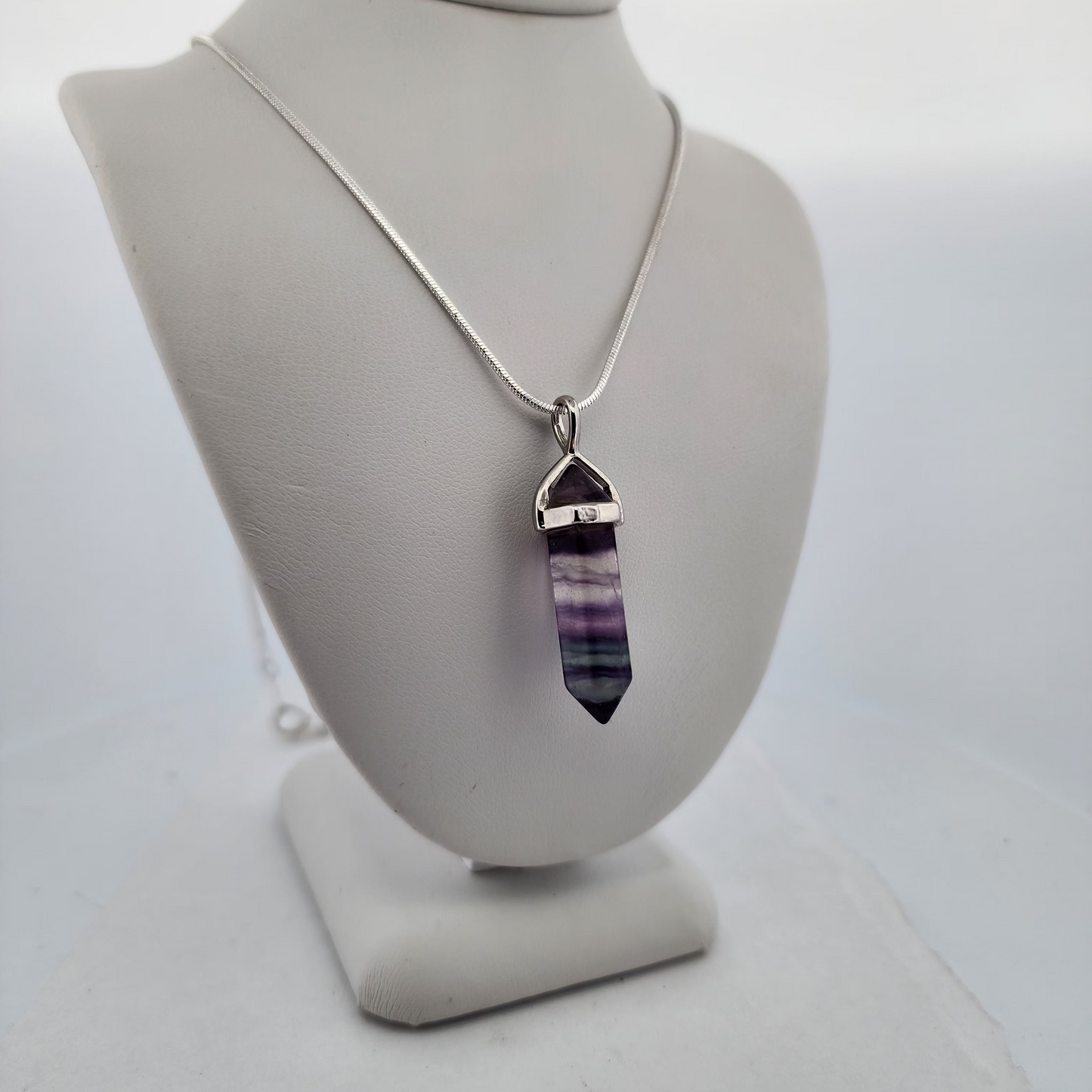Necklace with a purple crystal pendant on a white mannequin bust.