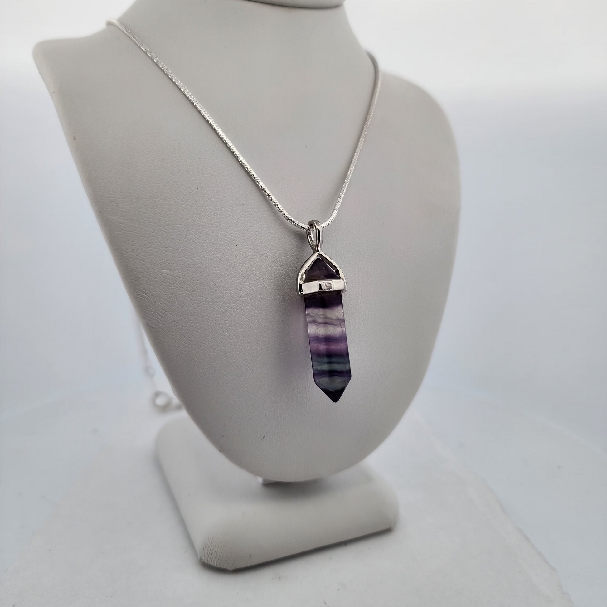 Necklace with a purple crystal pendant on a white mannequin bust.