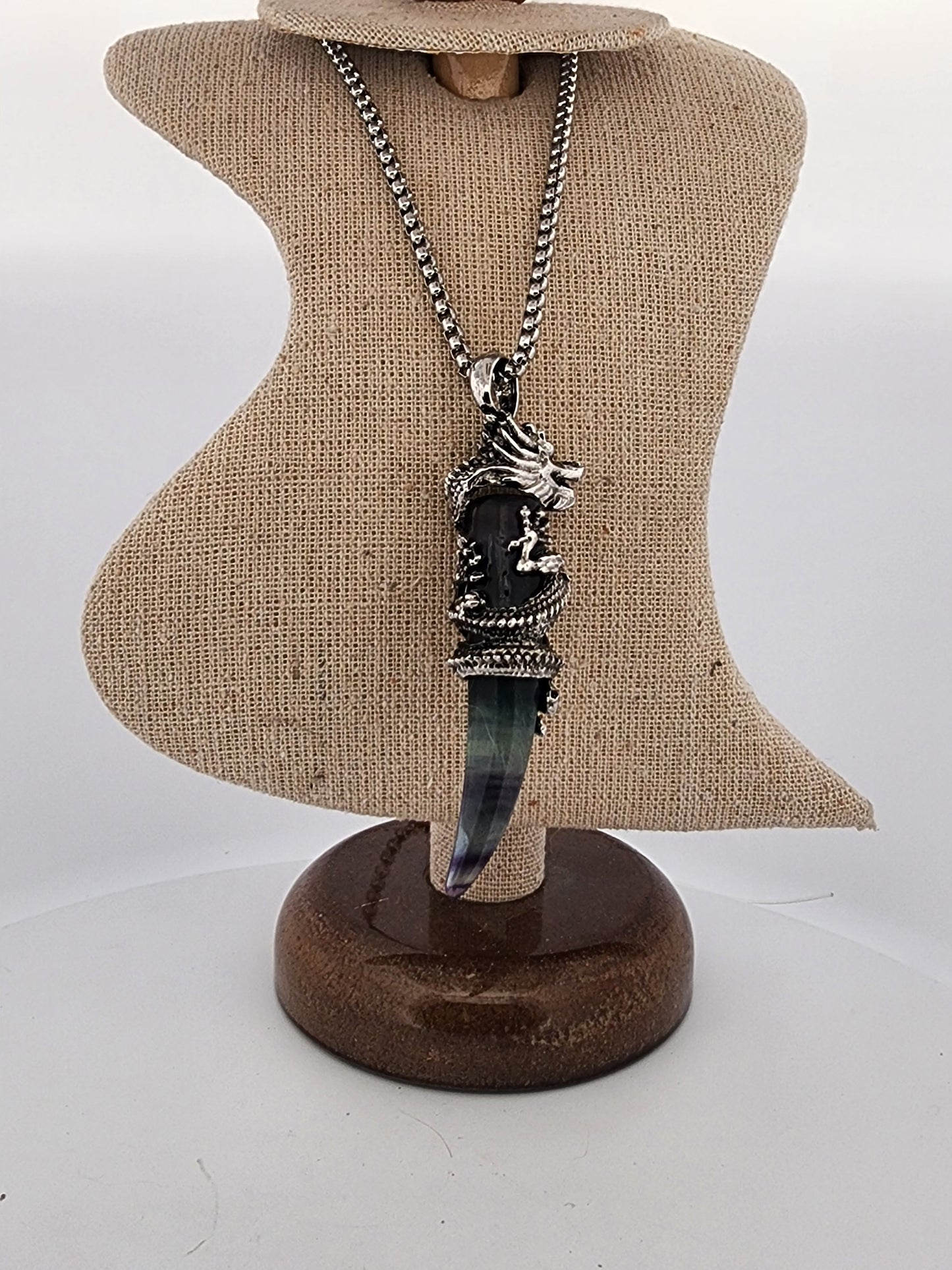 Necklace with a unique pendant on a brown display stand against a white background