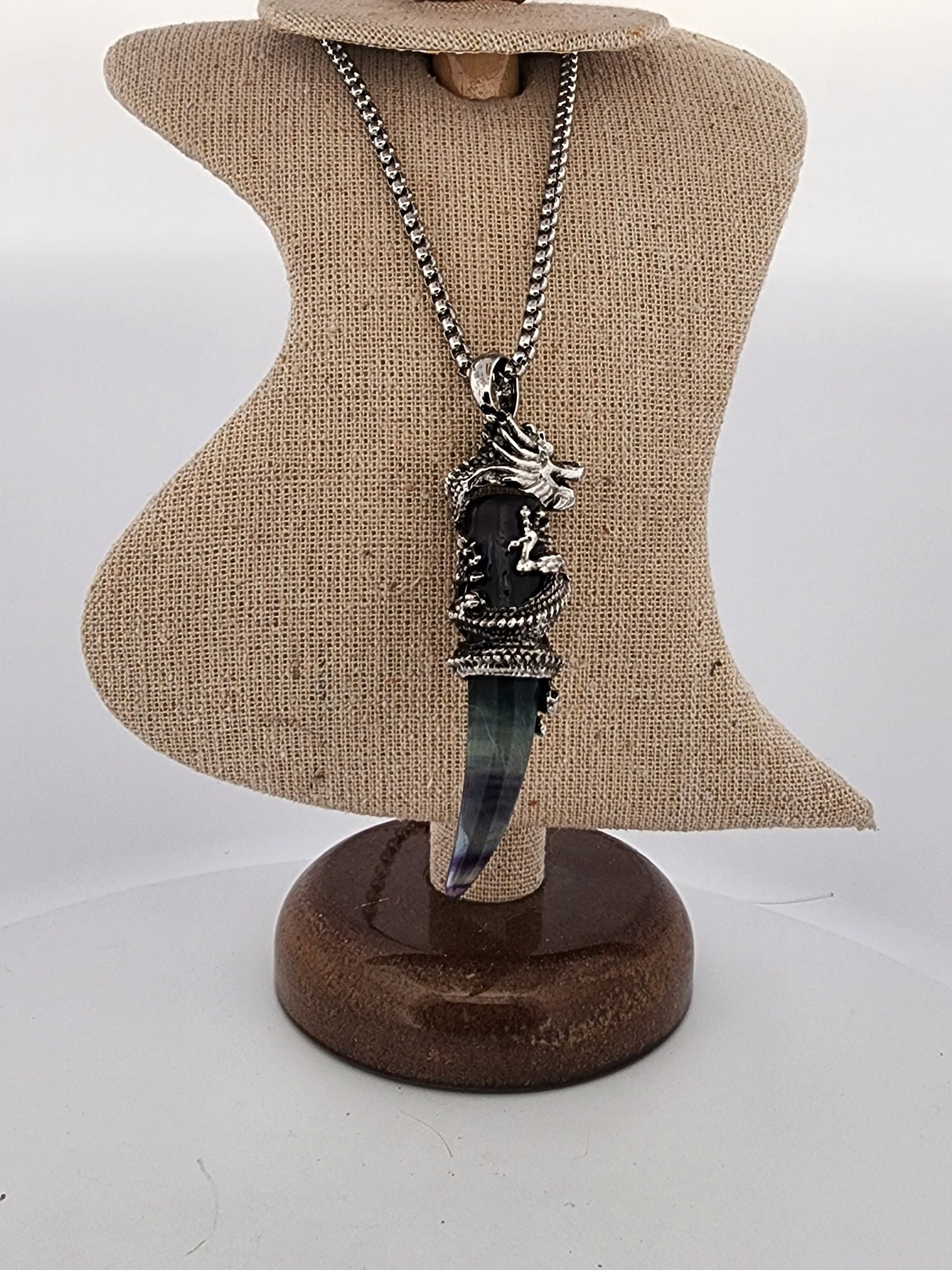 Necklace with a unique pendant on a brown display stand against a white background