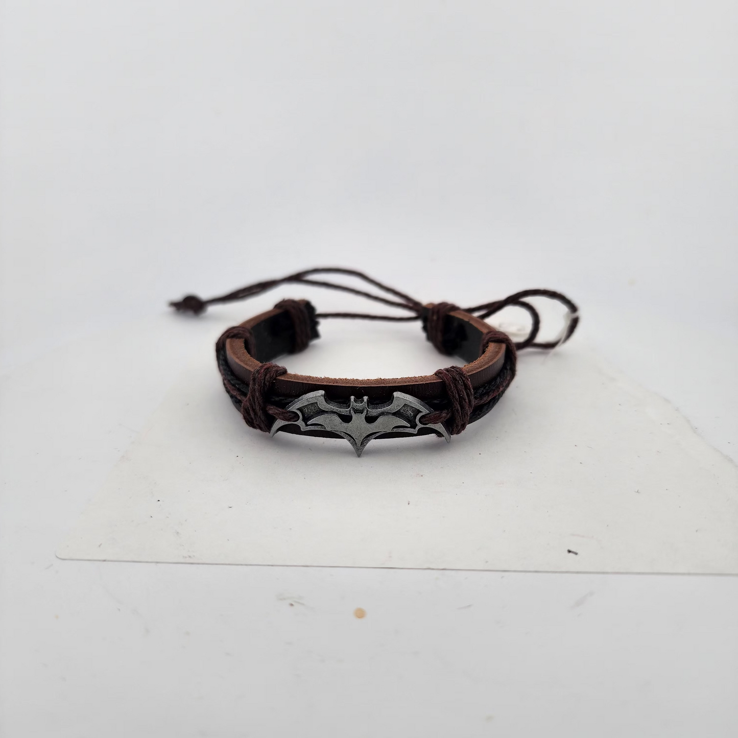 Brown leather bracelet with metal spider design on a white background