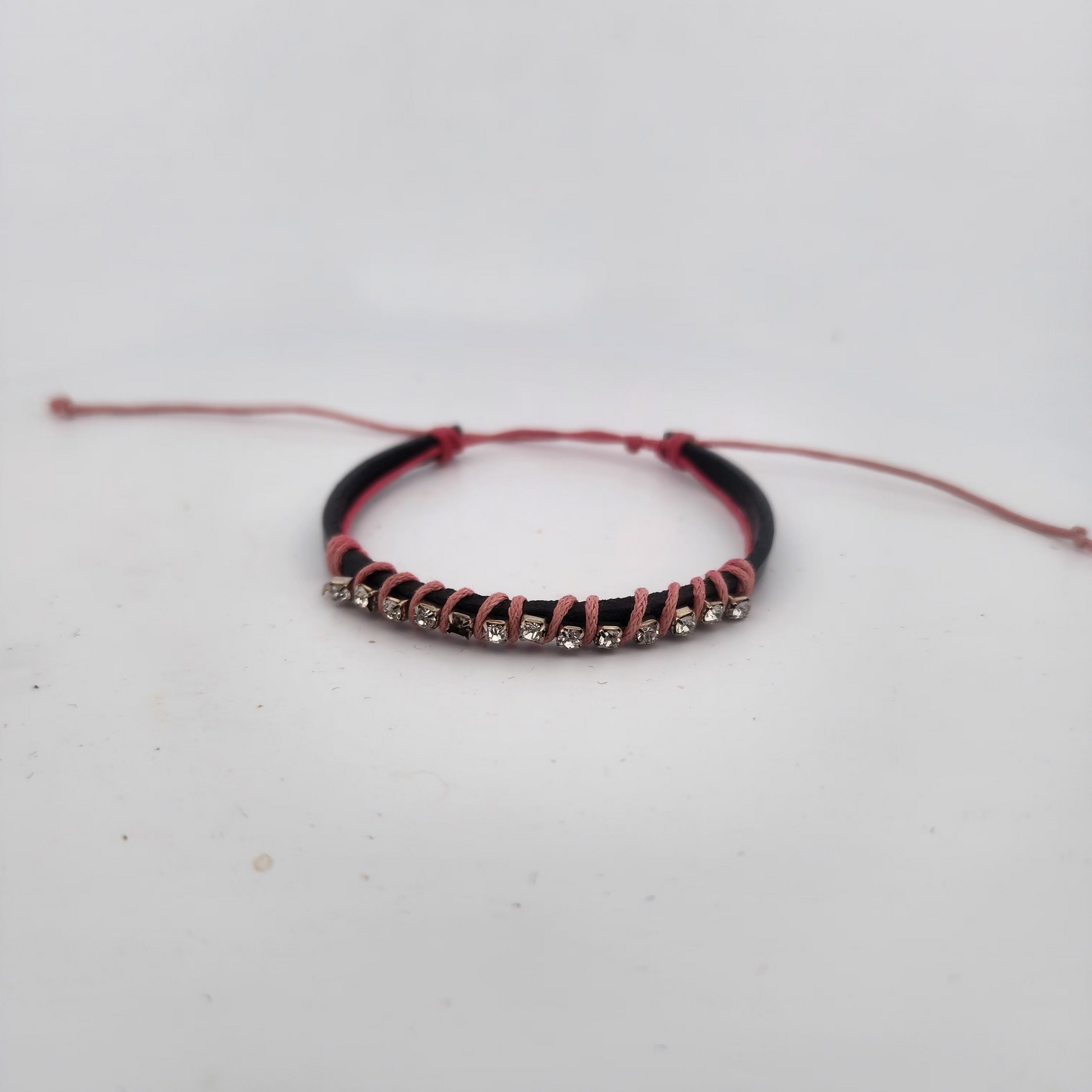 Bracelet with red cord and black band on a white background
