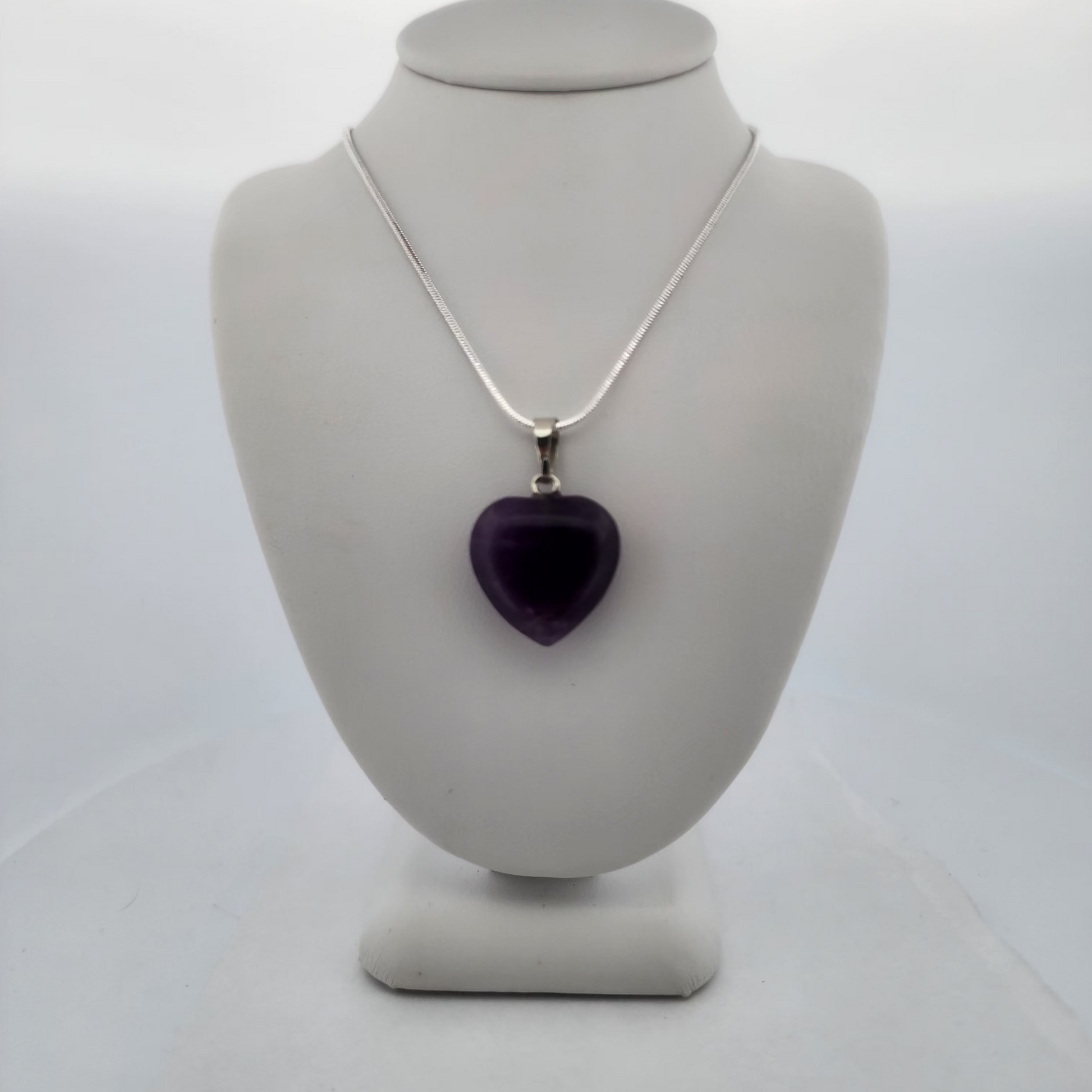 Necklace with a purple heart pendant on a gray mannequin bust against a white background