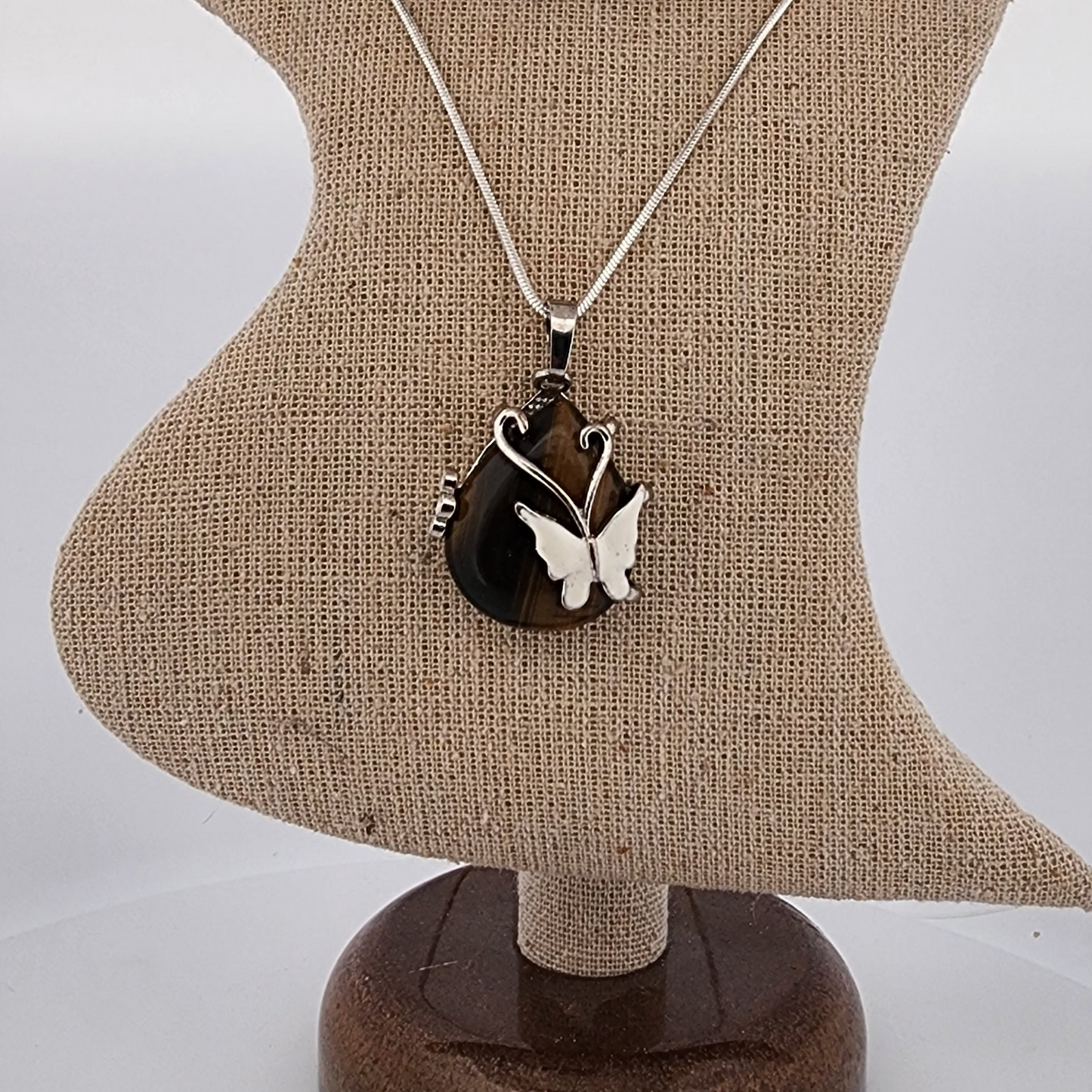 Butterfly pendant necklace on a mannequin bust with a plain background