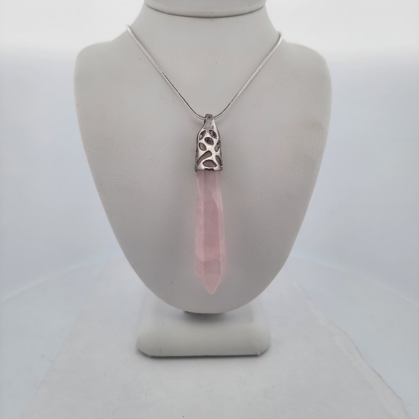 Necklace with a pink pendant on a mannequin bust against a white background