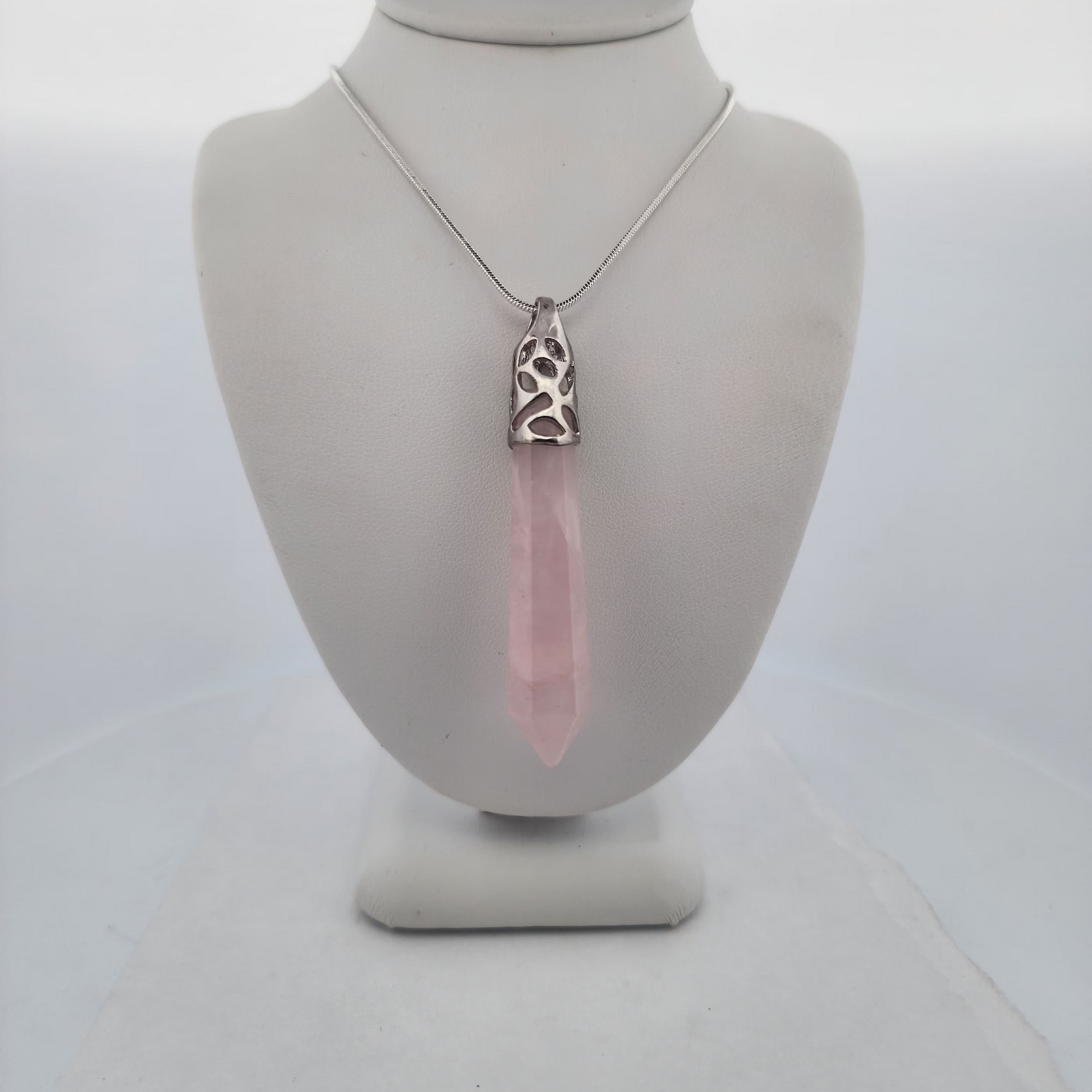 Necklace with a pink pendant on a mannequin bust against a white background