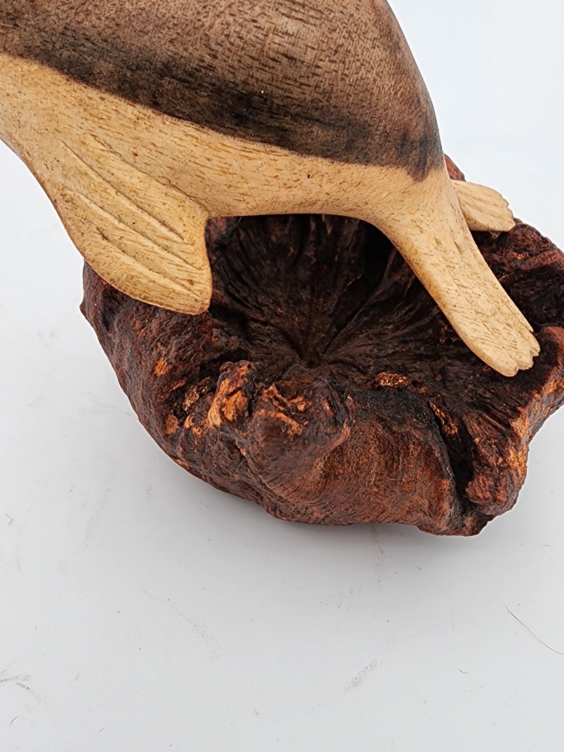 Wooden duckling figurine on a wooden mushroom base against a white background