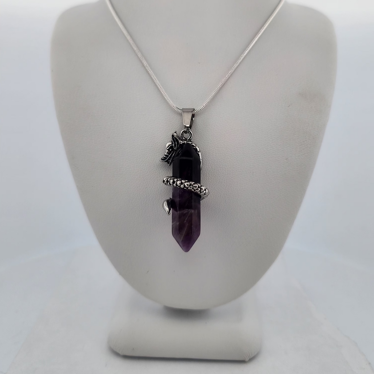 Necklace with a purple pendant on a white stand against a white background