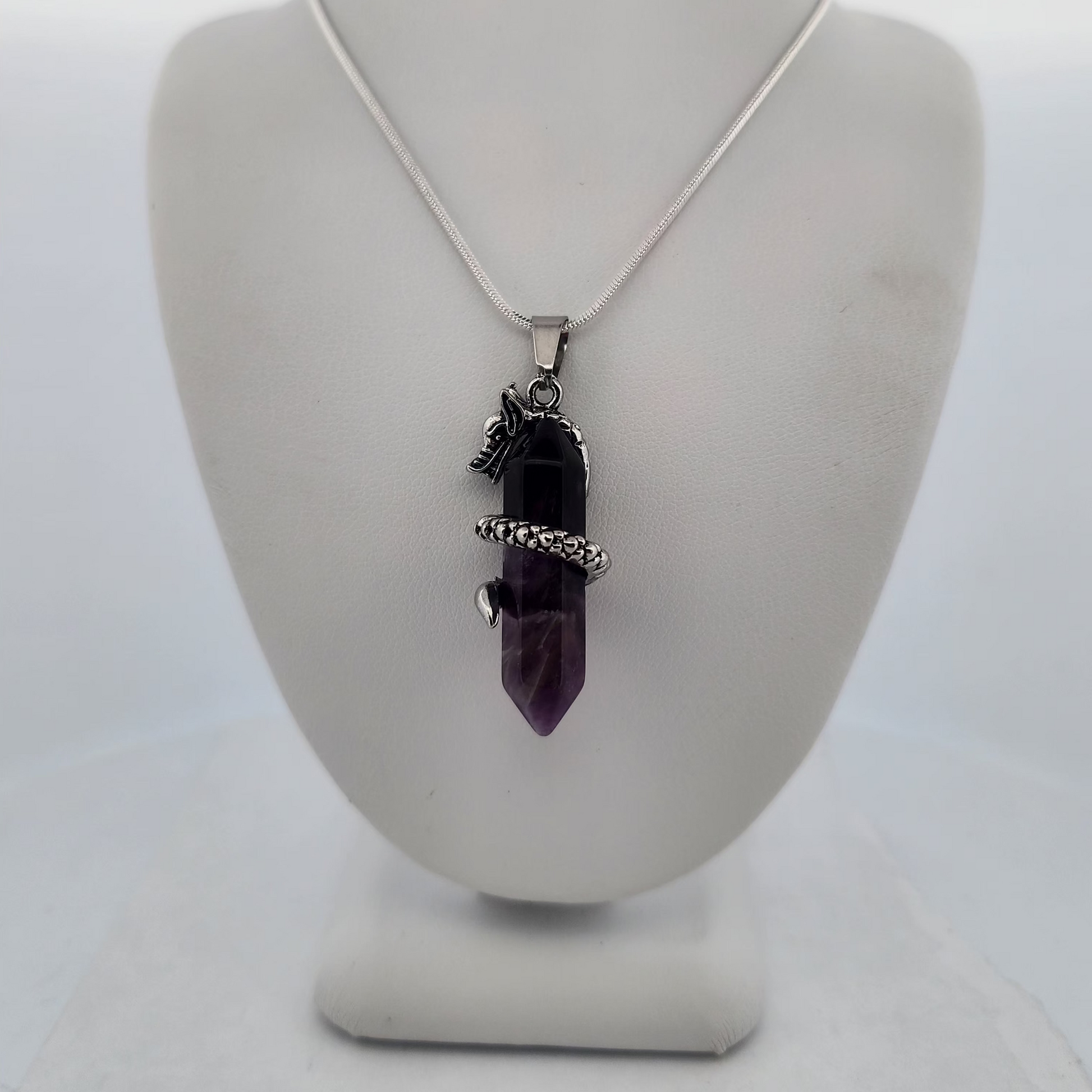 Necklace with a purple pendant on a white stand against a white background
