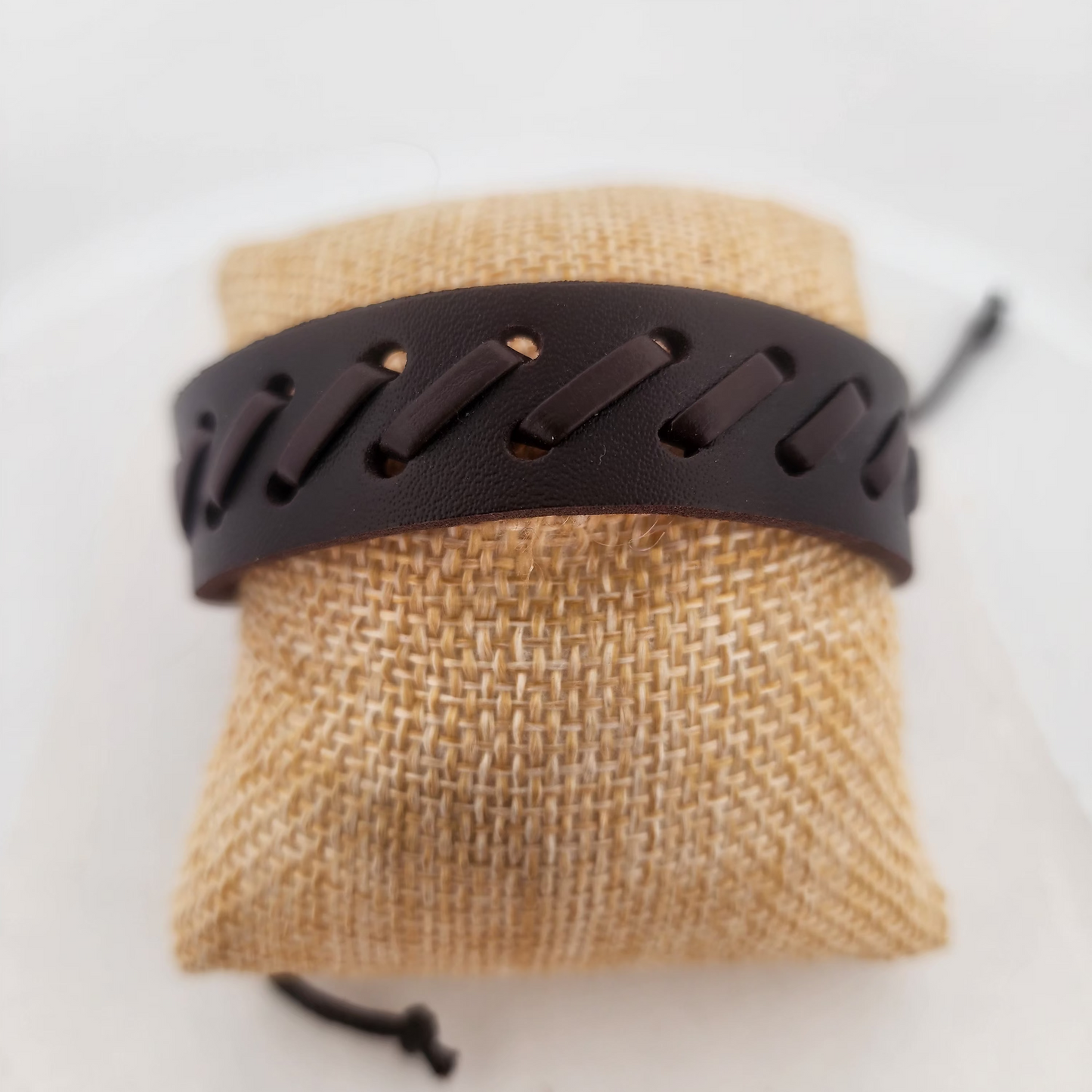 Brown woven pouch with a black leather strap on a white background