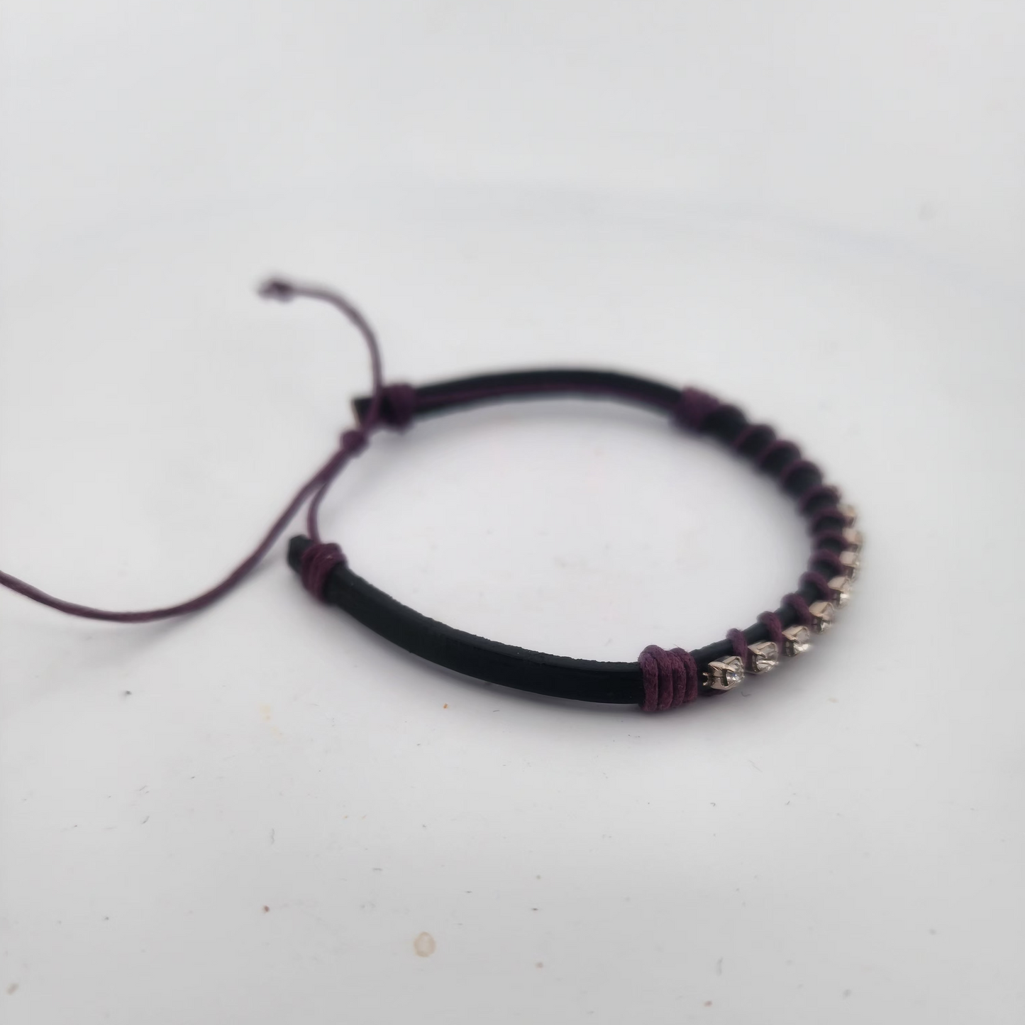 Bracelet with black cord and silver beads on a light gray background