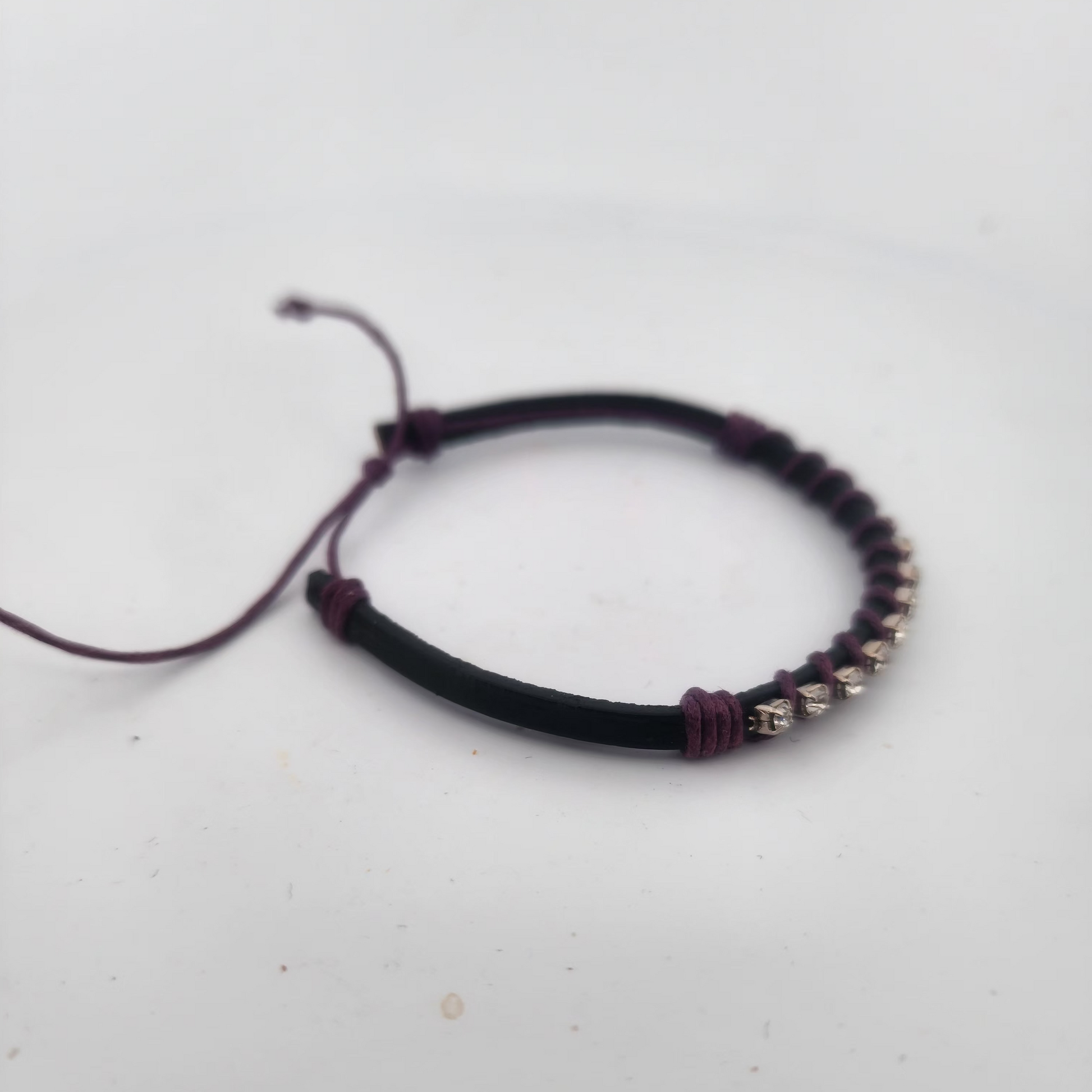Bracelet with black cord and silver beads on a light gray background