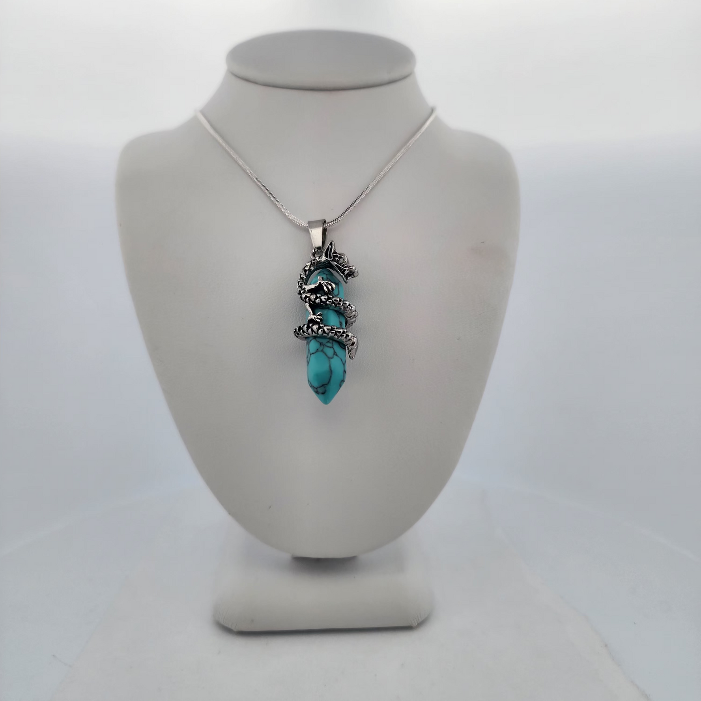 Turquoise pendant necklace on a mannequin bust against a white background
