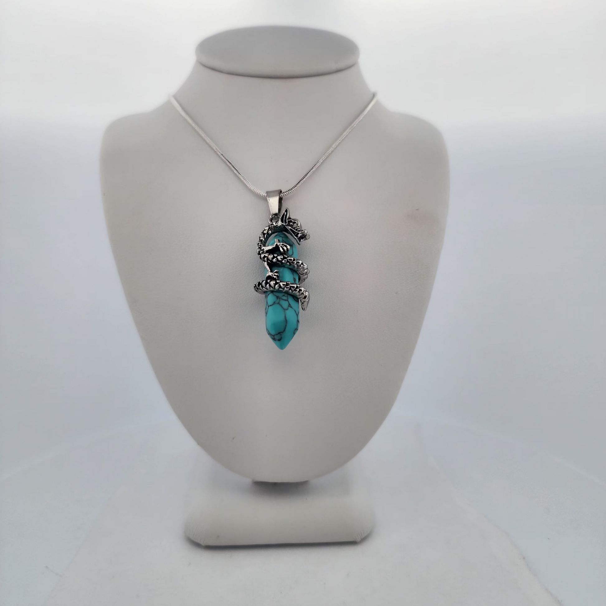 Turquoise pendant necklace on a mannequin bust against a white background