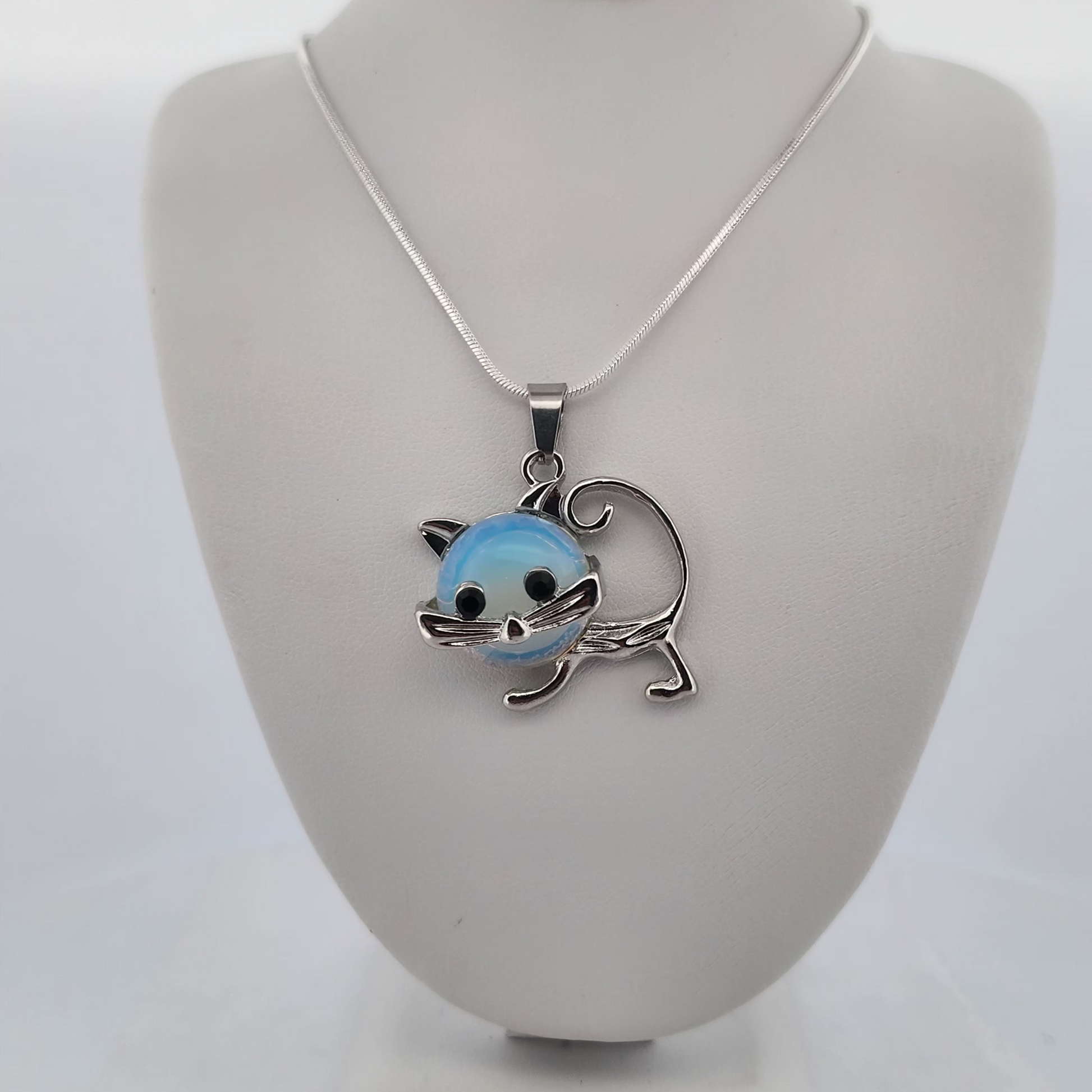 Cat-shaped pendant on a necklace displayed on a gray bust