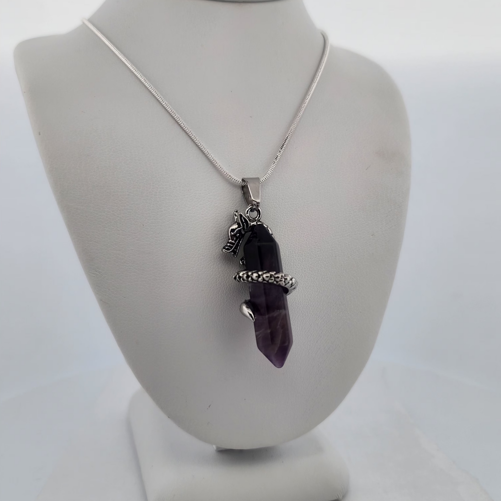 Necklace with a purple crystal pendant on a white stand