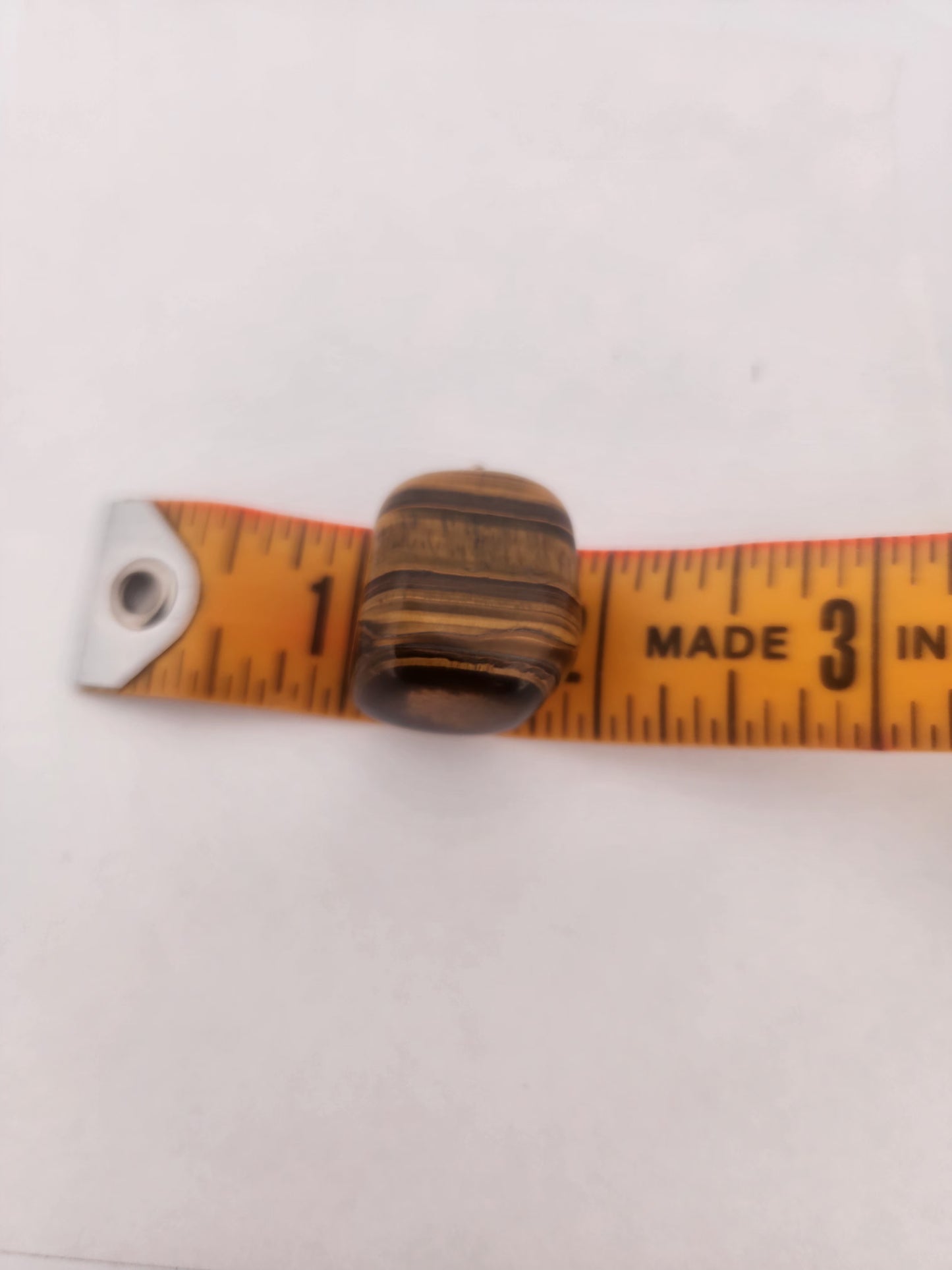 Small Tiger eye being measured with a tape measure on a white background