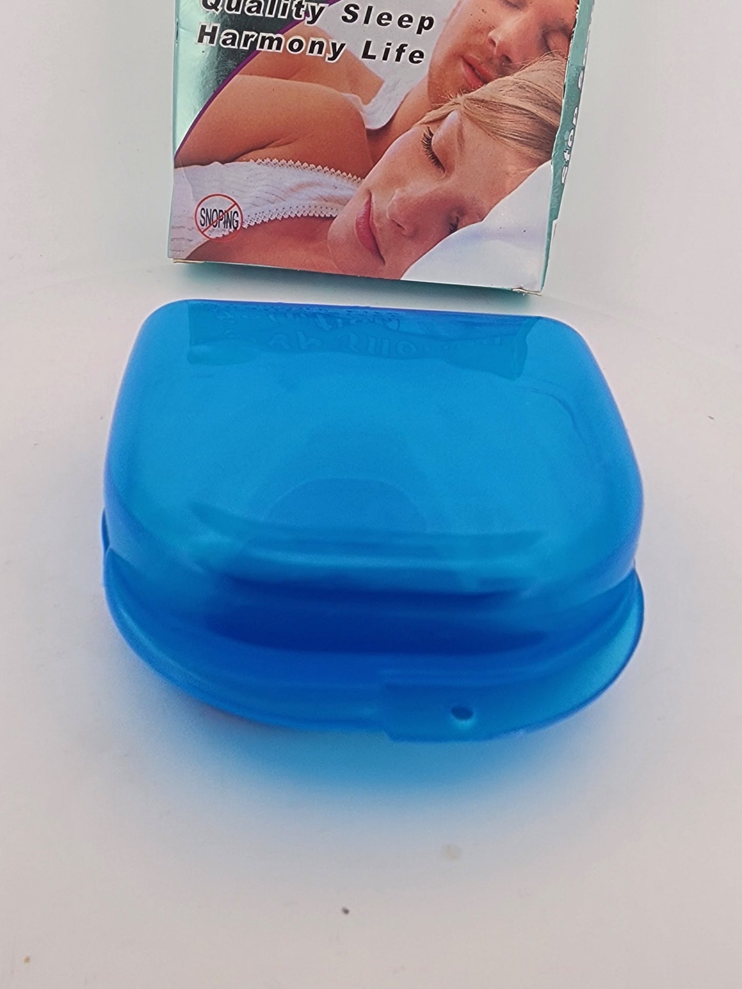 Blue device on a white surface with a product packaging in the background.
