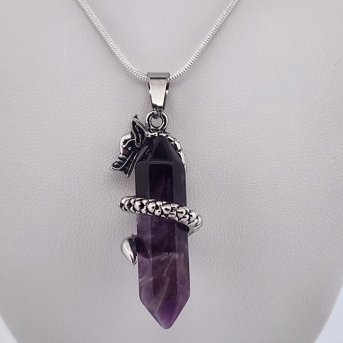Amethyst crystal pendant with silver accents on a white background