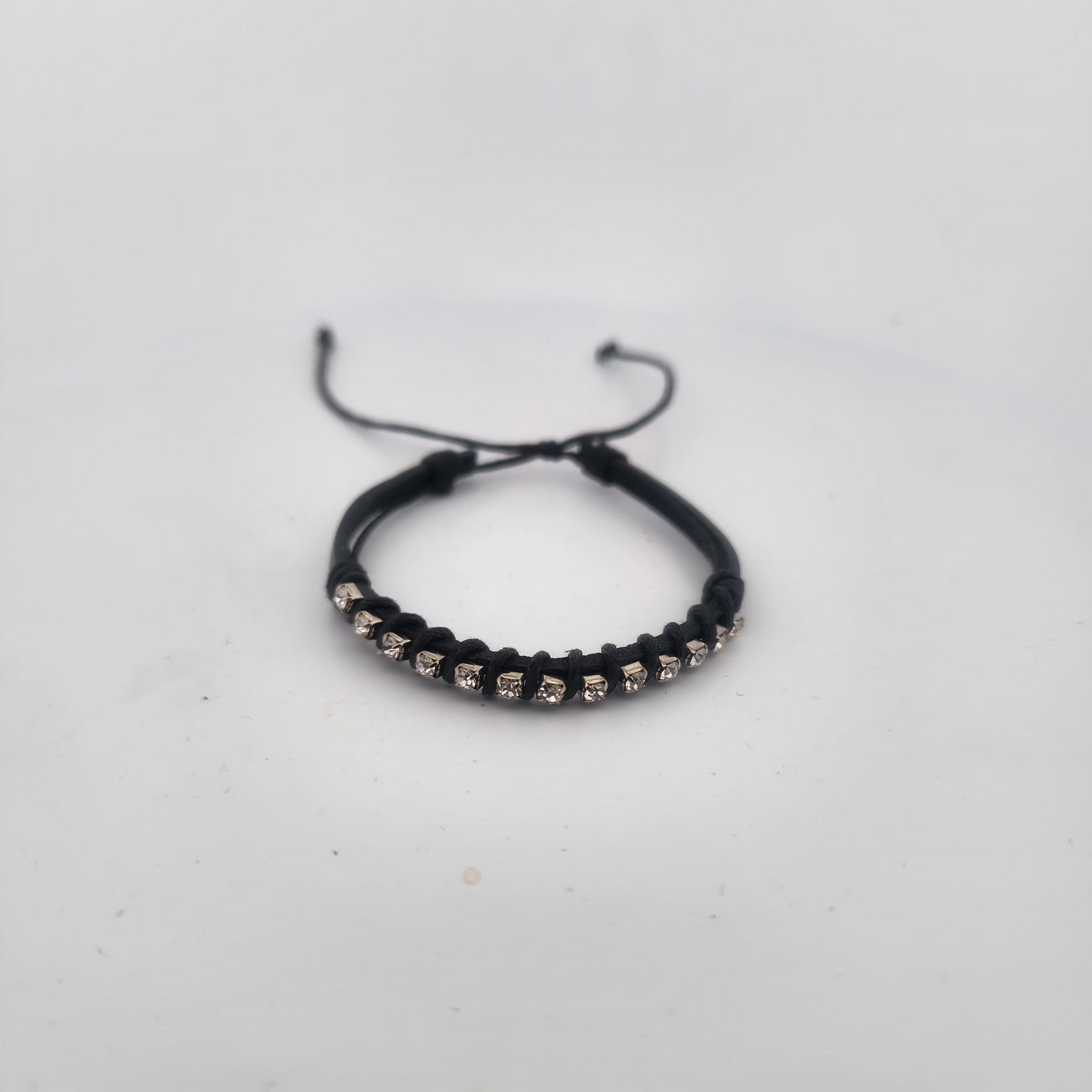 Black braided bracelet with small beads on a light gray background