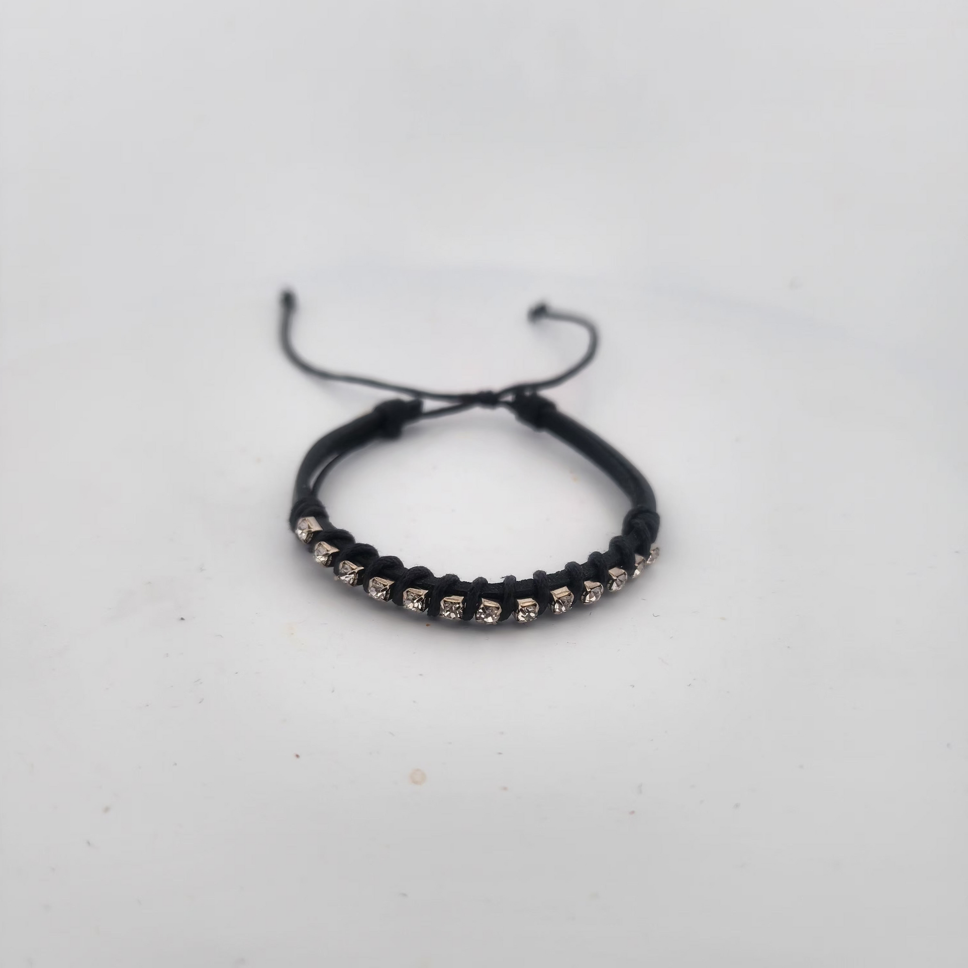 Black braided bracelet with small beads on a light gray background