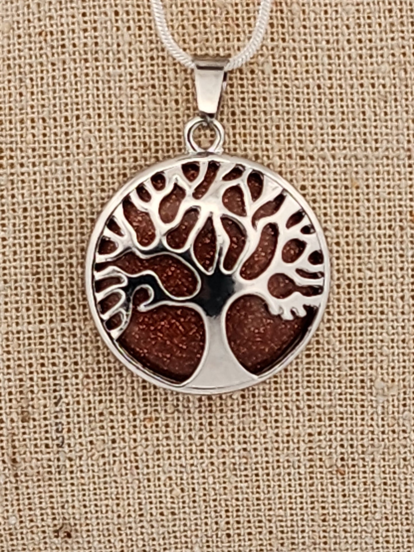 Tree of life pendant on a beige fabric background
