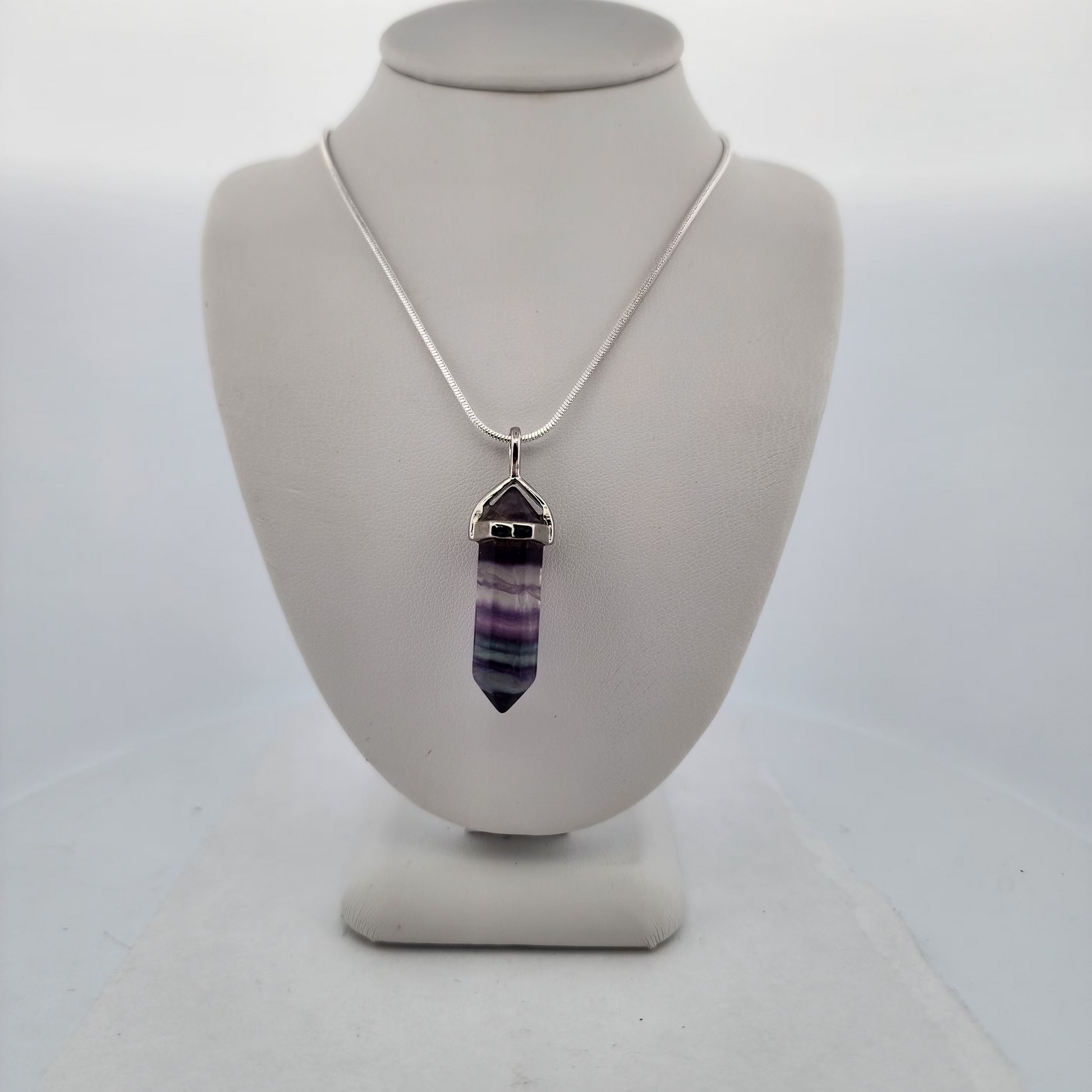 Necklace with a multicolored pendant on a white bust against a white background