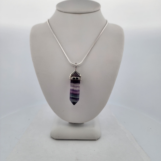 Necklace with a multicolored pendant on a white bust against a white background