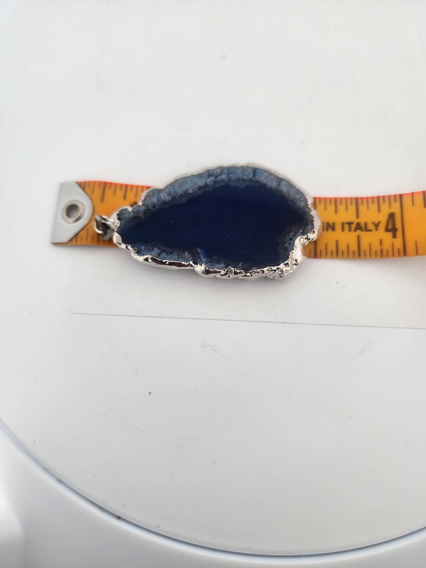 Blue stone pendant on a measuring tape against a white background