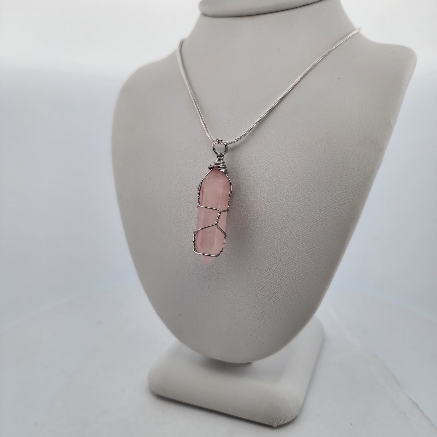 Necklace with a pink pendant on a gray bust against a white background