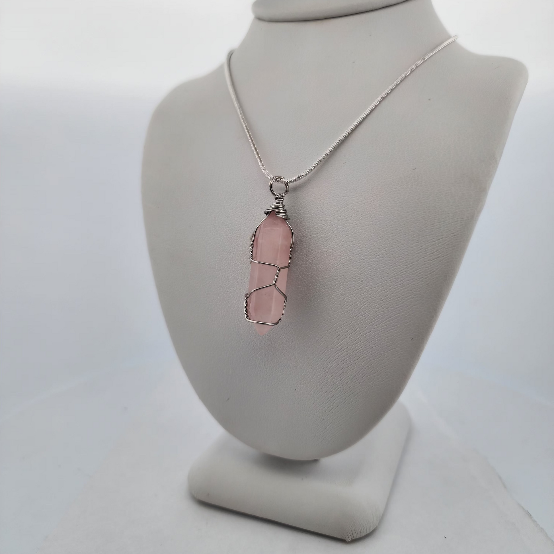 Necklace with a pink pendant on a gray bust against a white background