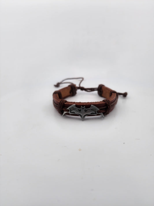 Brown leather bracelet with a silver bat-shaped clasp on a white background