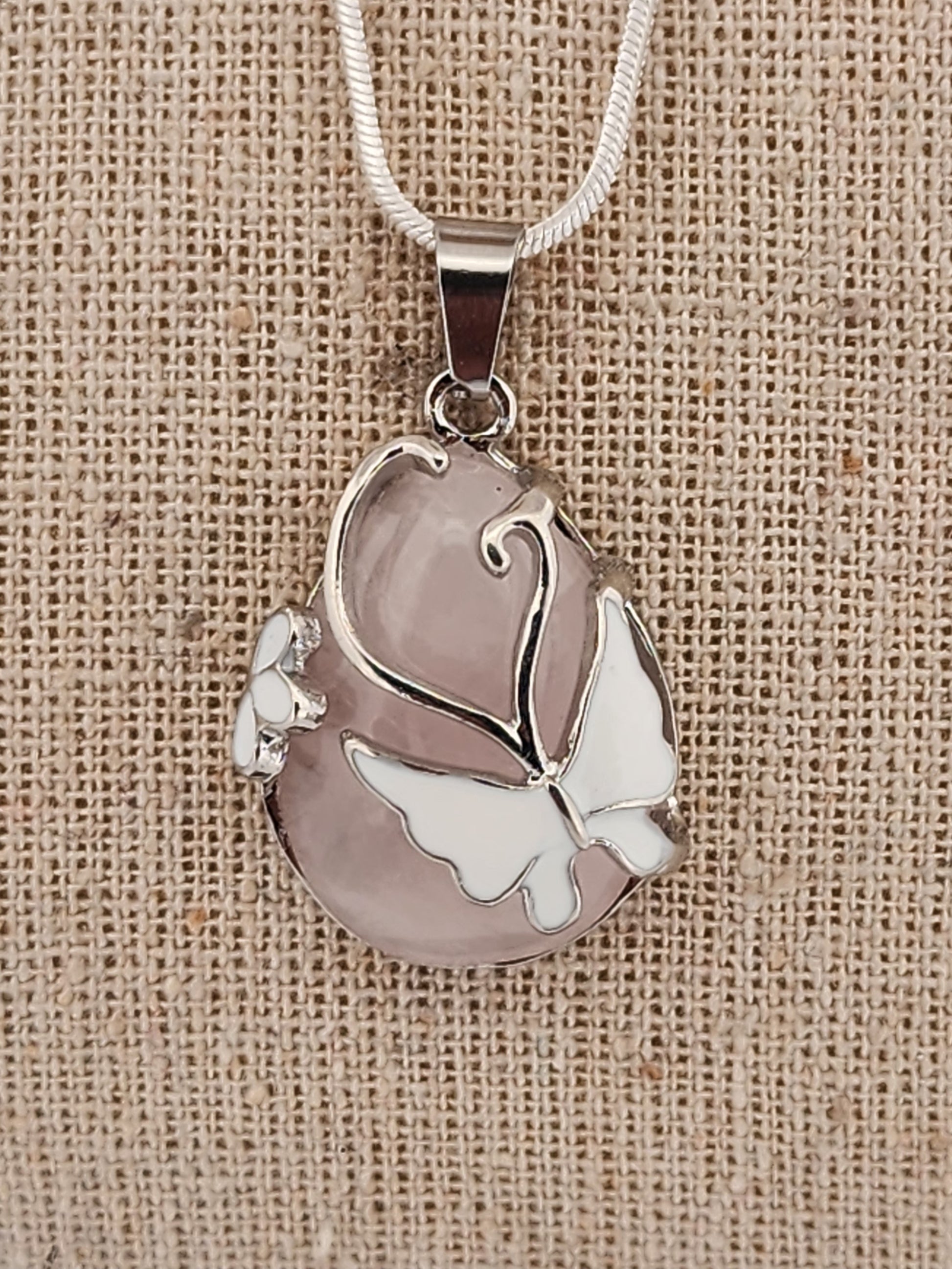 Silver butterfly pendant on a beige fabric background