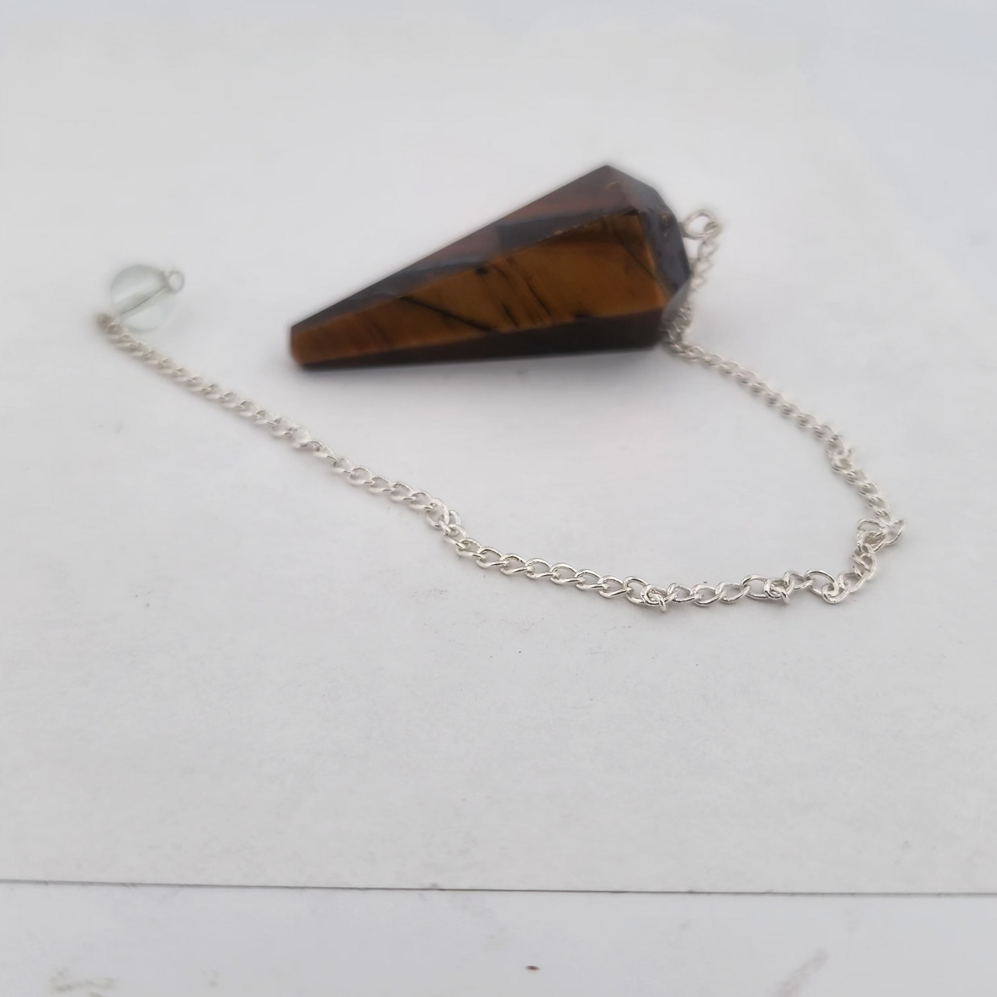 Tiger eye crystal pendant on a chain against a white background