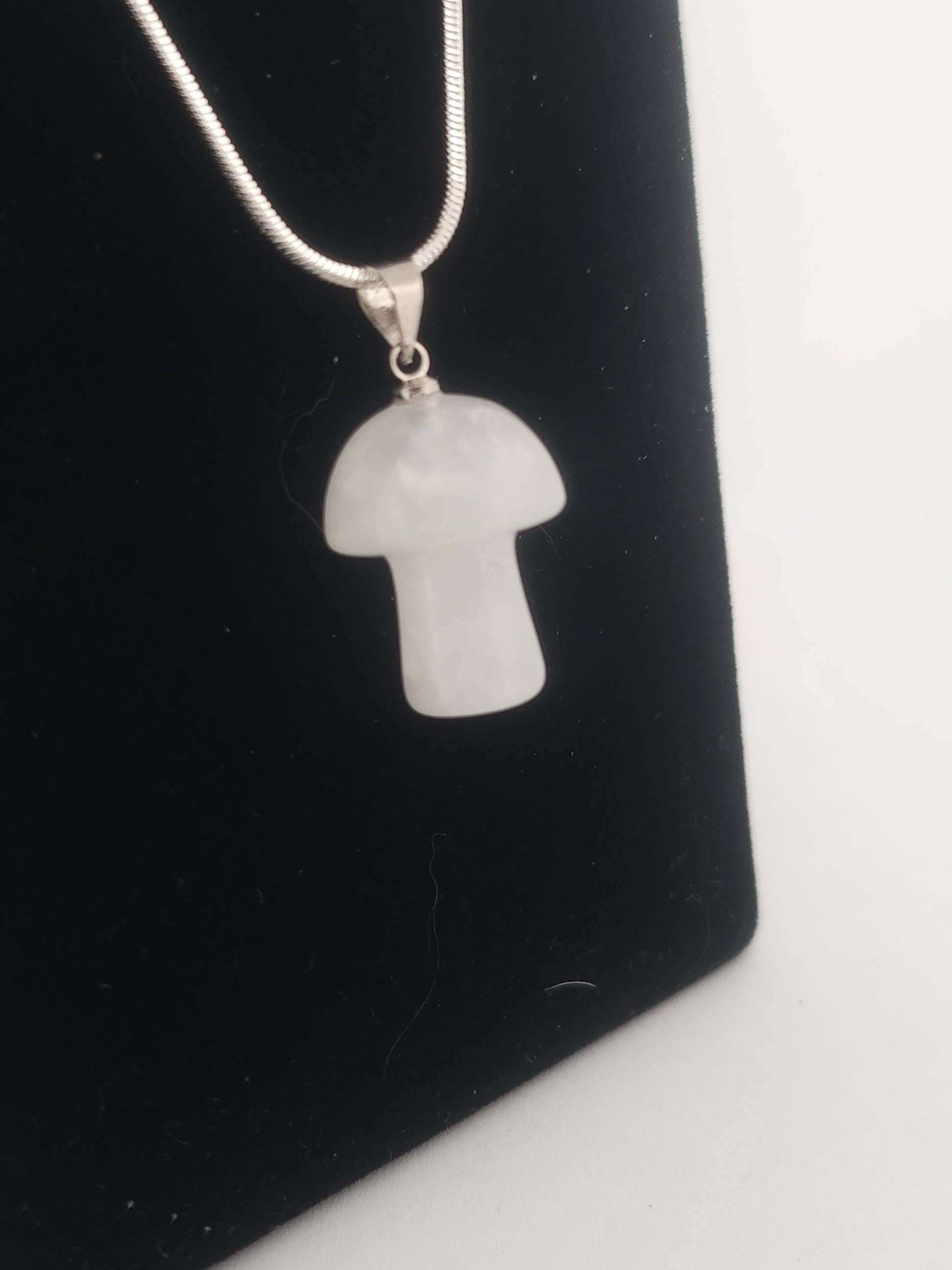 White stone pendant on a chain against a black background