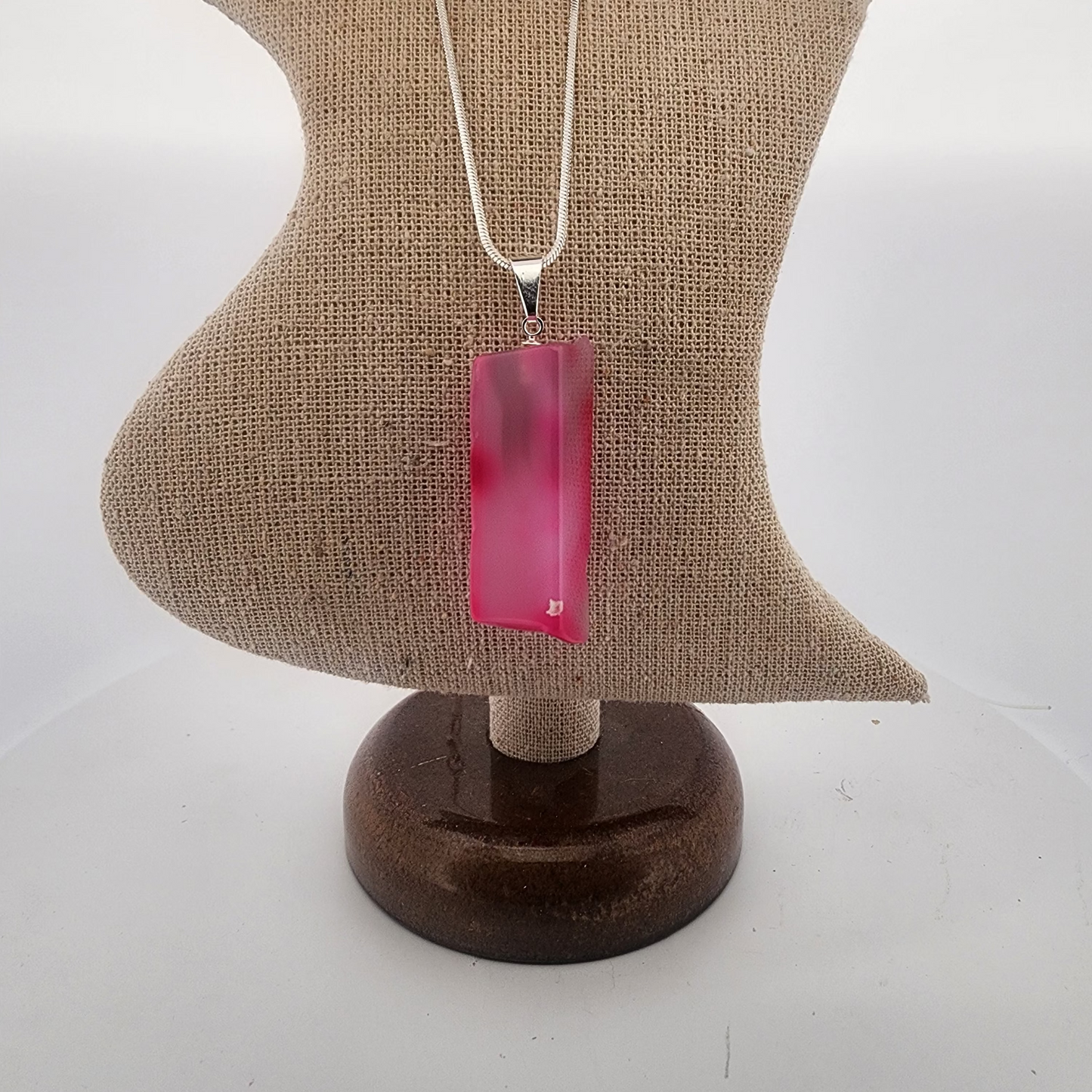 Necklace with a pink pendant on a mannequin bust against a white background