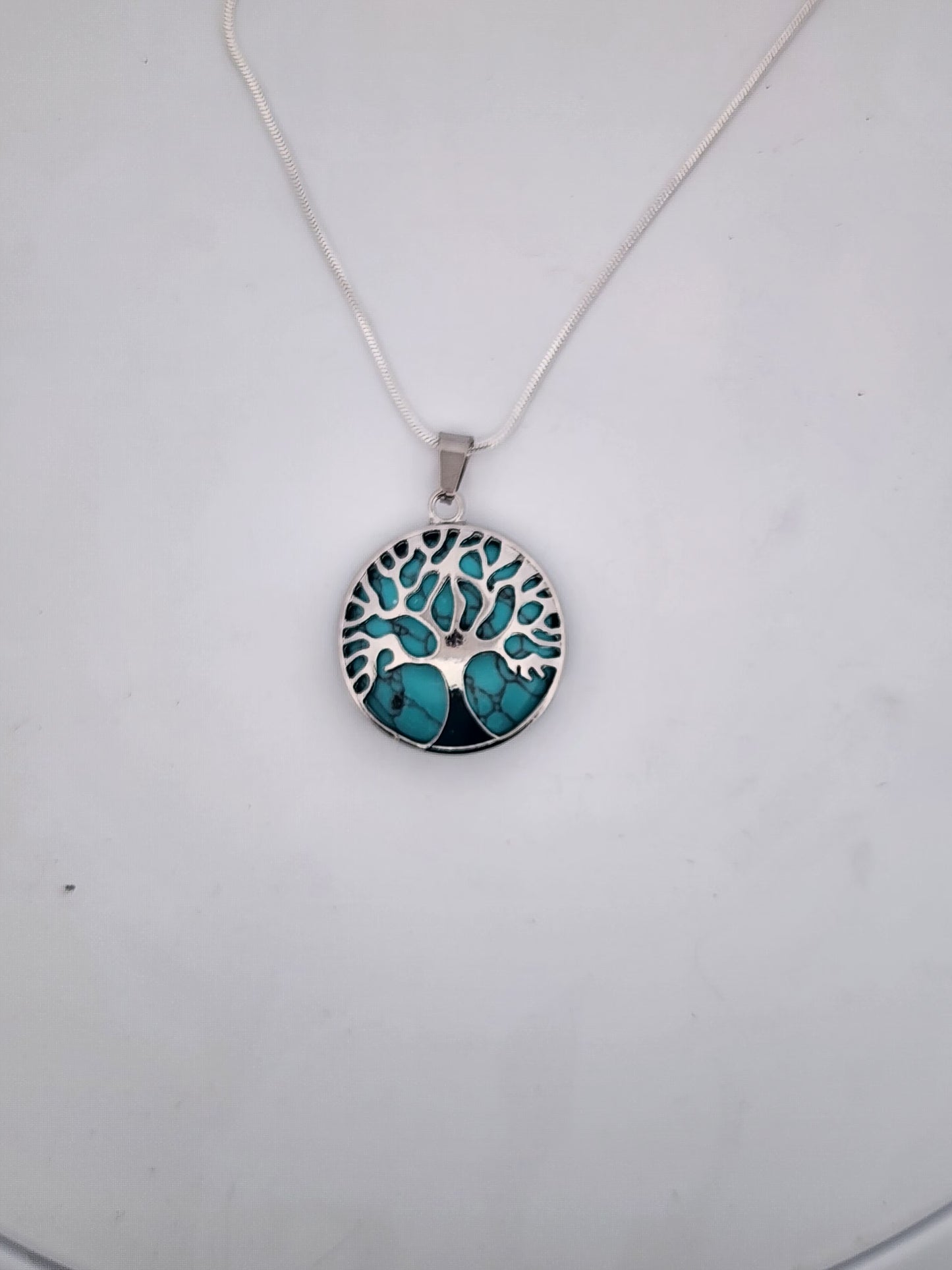Necklace with a tree of life pendant featuring turquoise stones on a white background